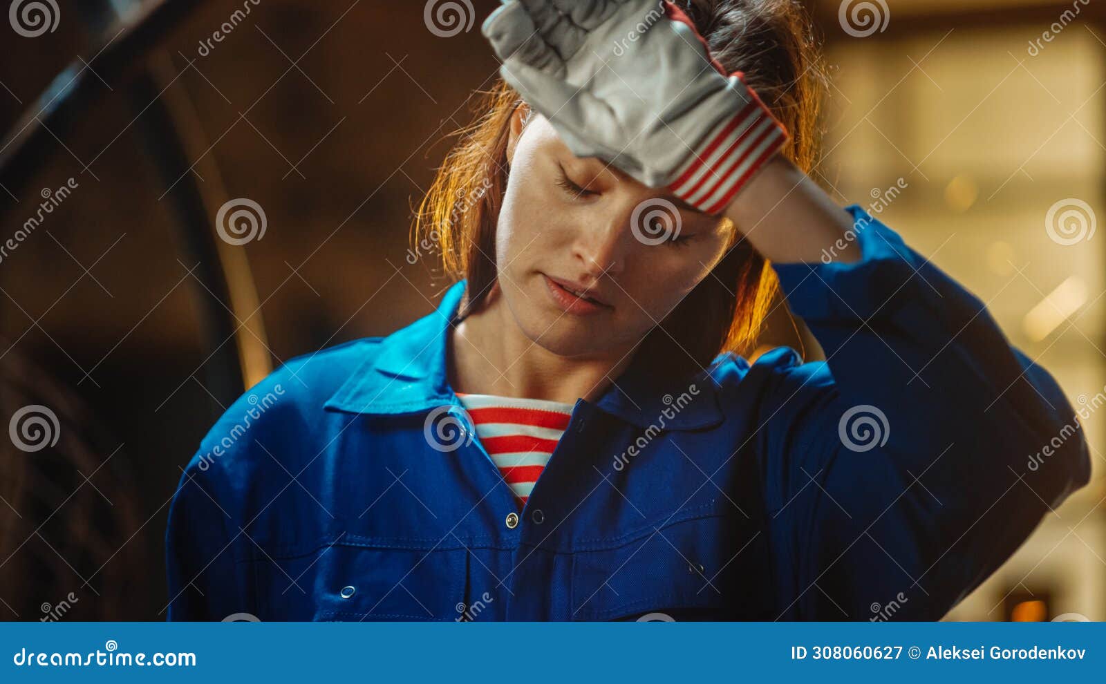 young beautiful empowering woman rubs her forehead. authentic fabricator wearing work clothes in a