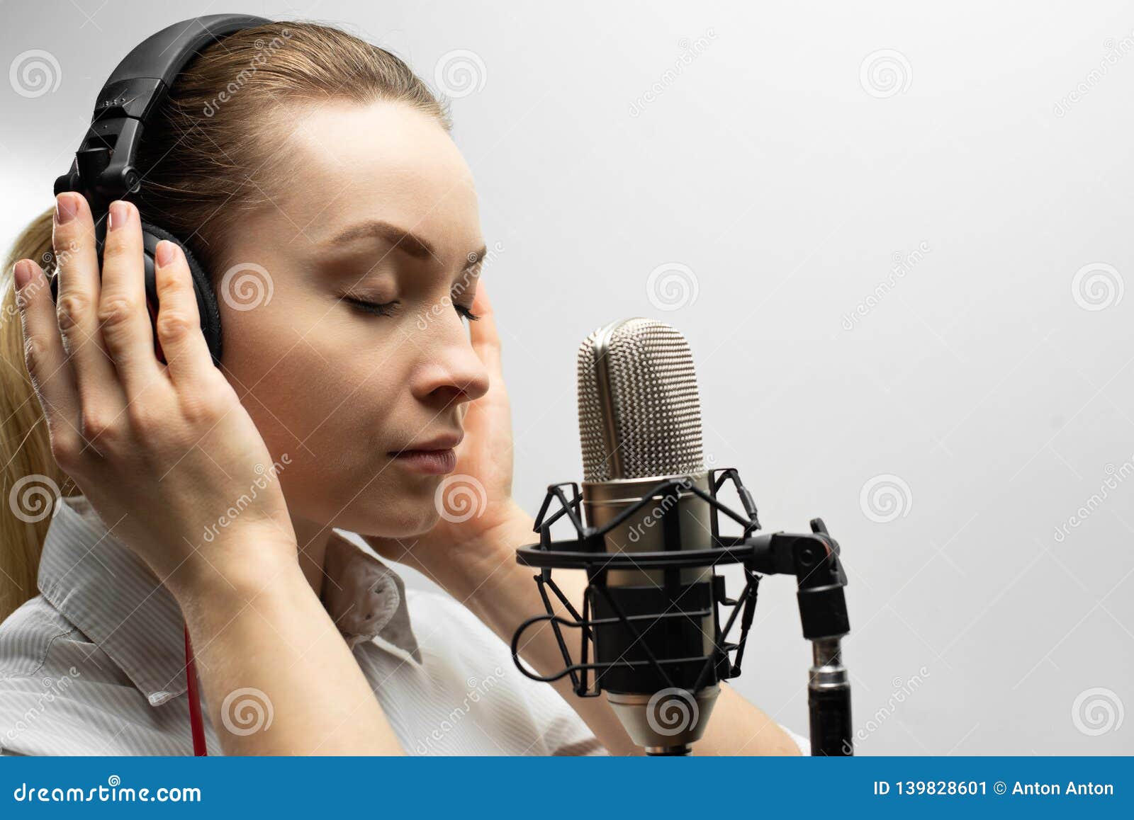 young beautiful girl writes vocals, radio, voiceover tv, reads poetry, blog, podcast in studio on studio microphone in headphones