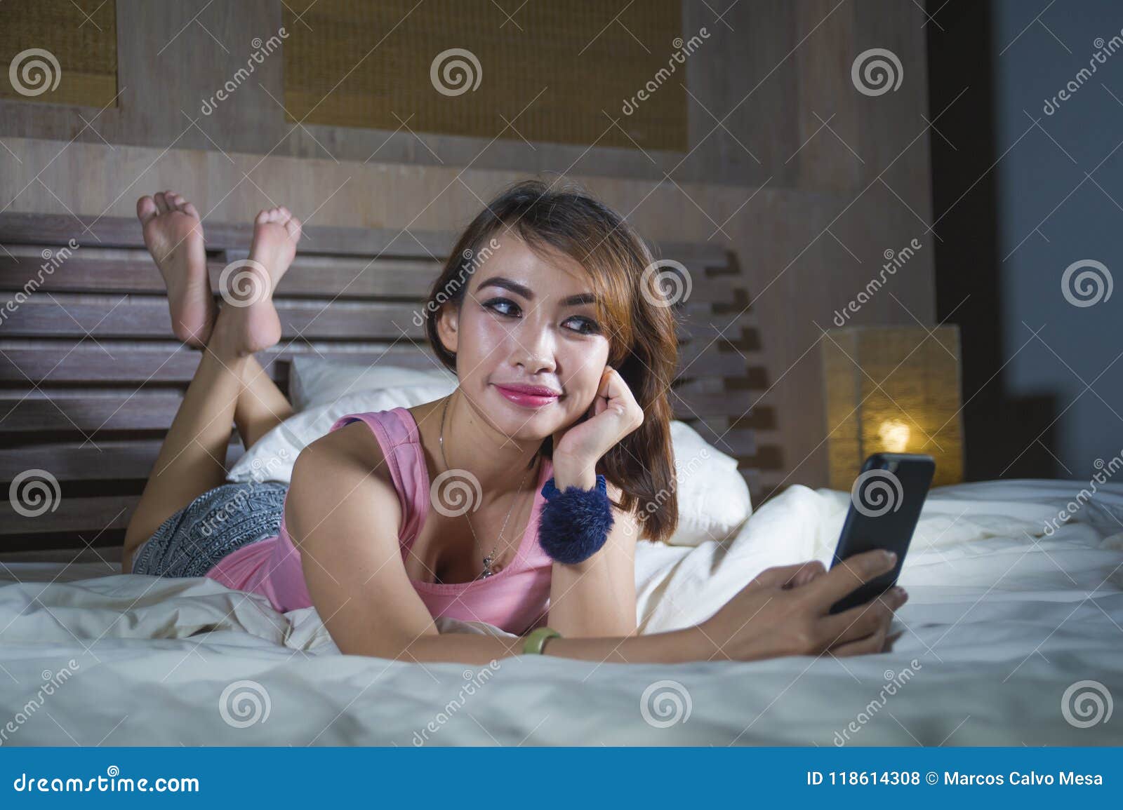 Young Beautiful And Happy Girl Lying On Bed Smiling And Flirting On Internet Social Media App