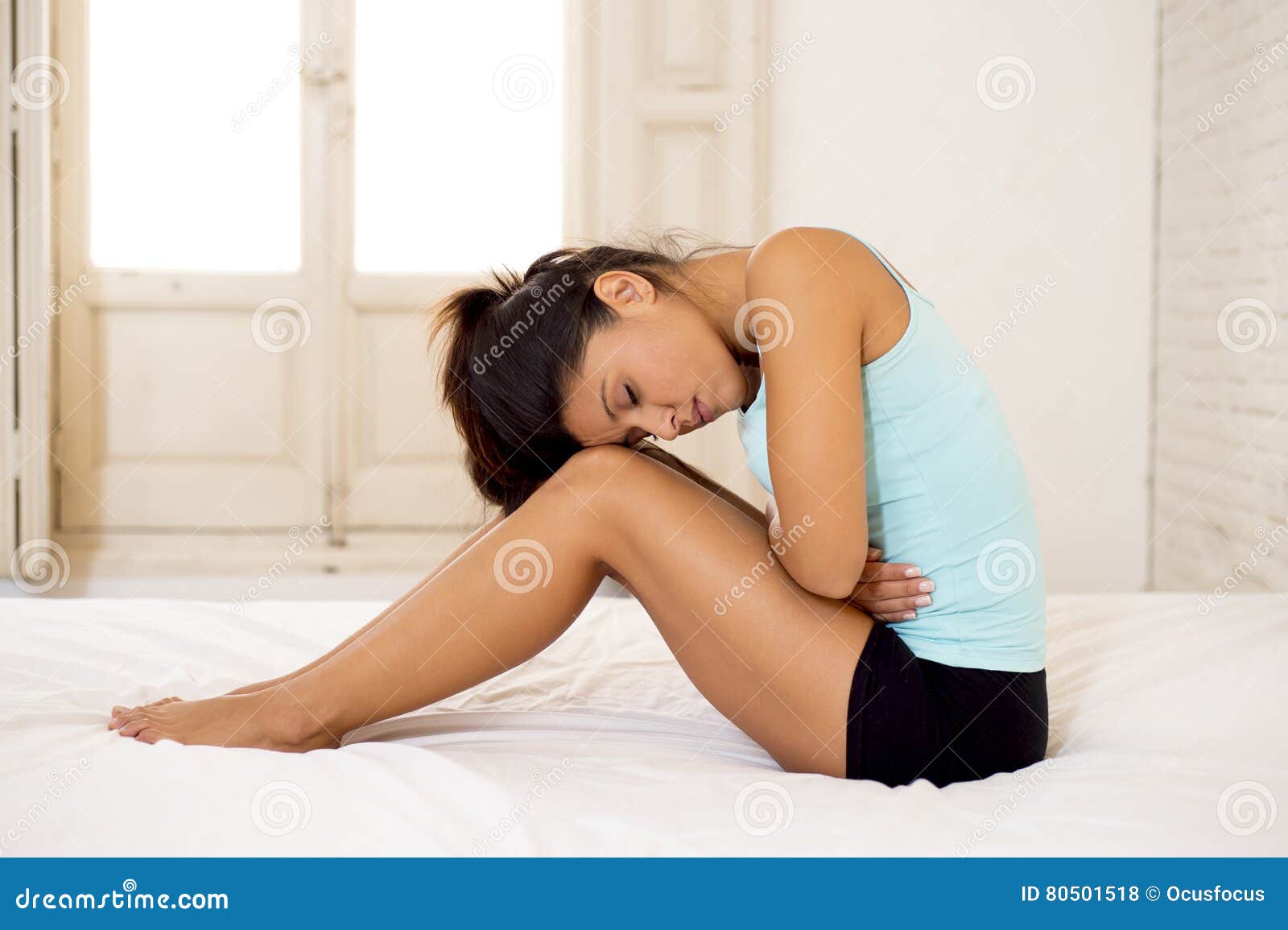 young beautiful hispanic woman holding belly suffering menstrual period pain