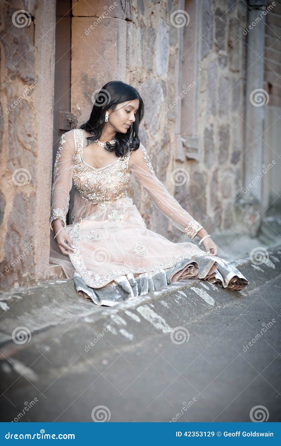 Young Beautiful Indian Woman Sitting Against Stone Wall 
