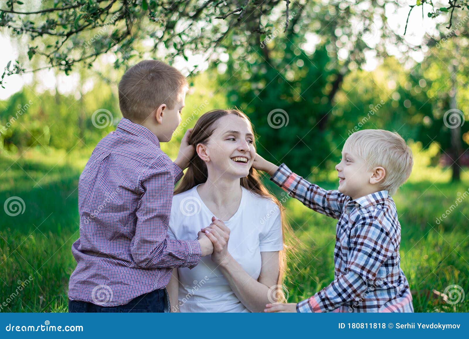 Young Beautiful Mother Playing with His Two Sons. Children Stroking Mom