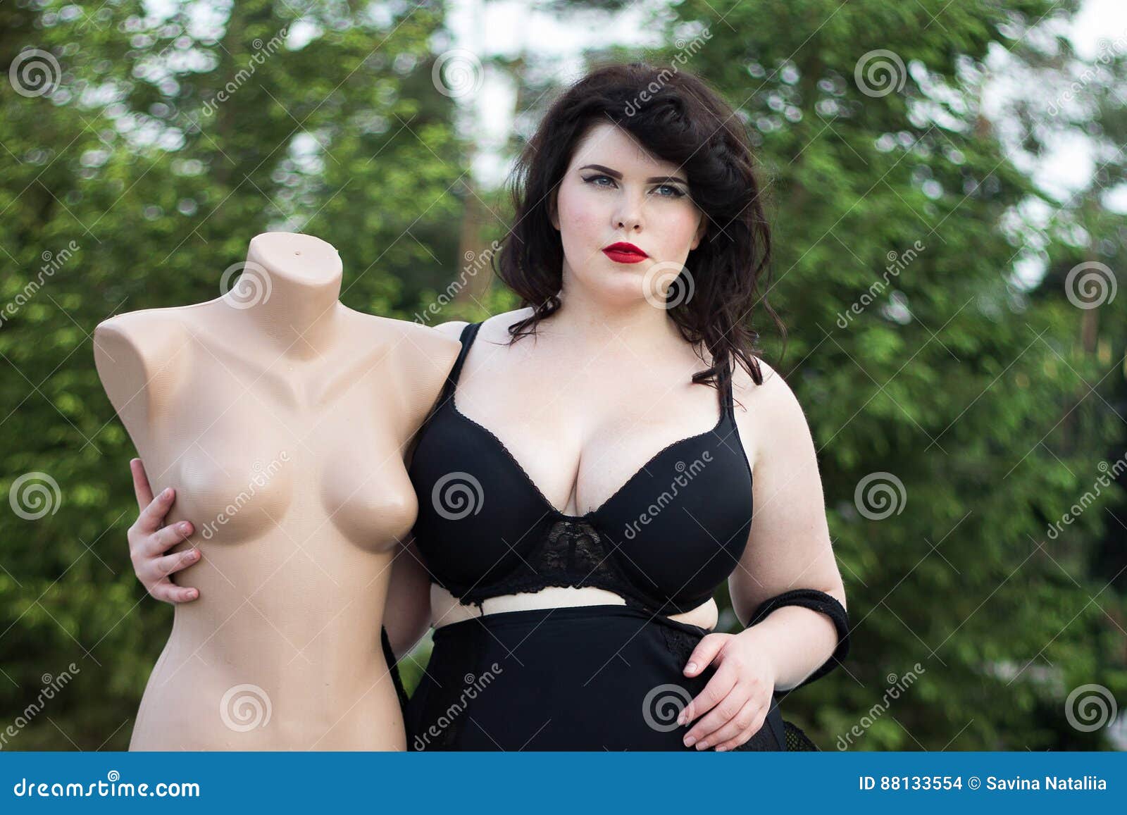 Young Beautiful Plus Size Modelt in Black Bra Holding Mannequin