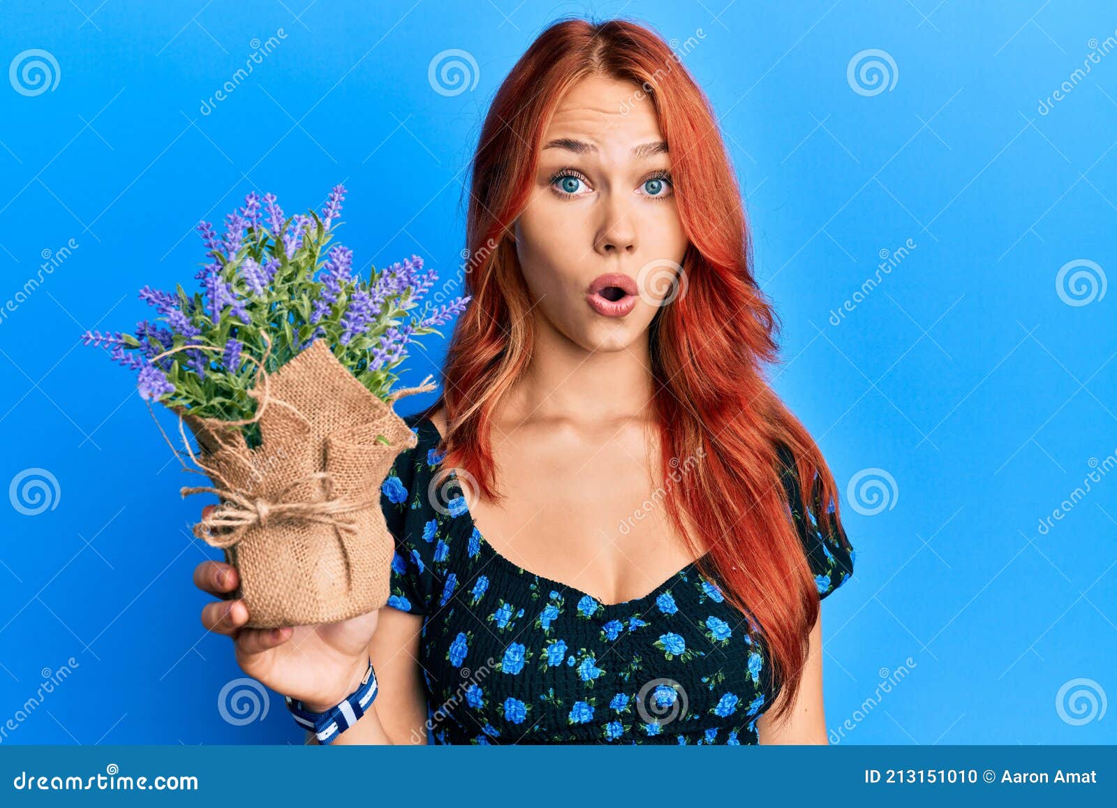 Young Beautiful Redhead Woman Holding Lavender Pot Scared And Amazed With Open Mouth For