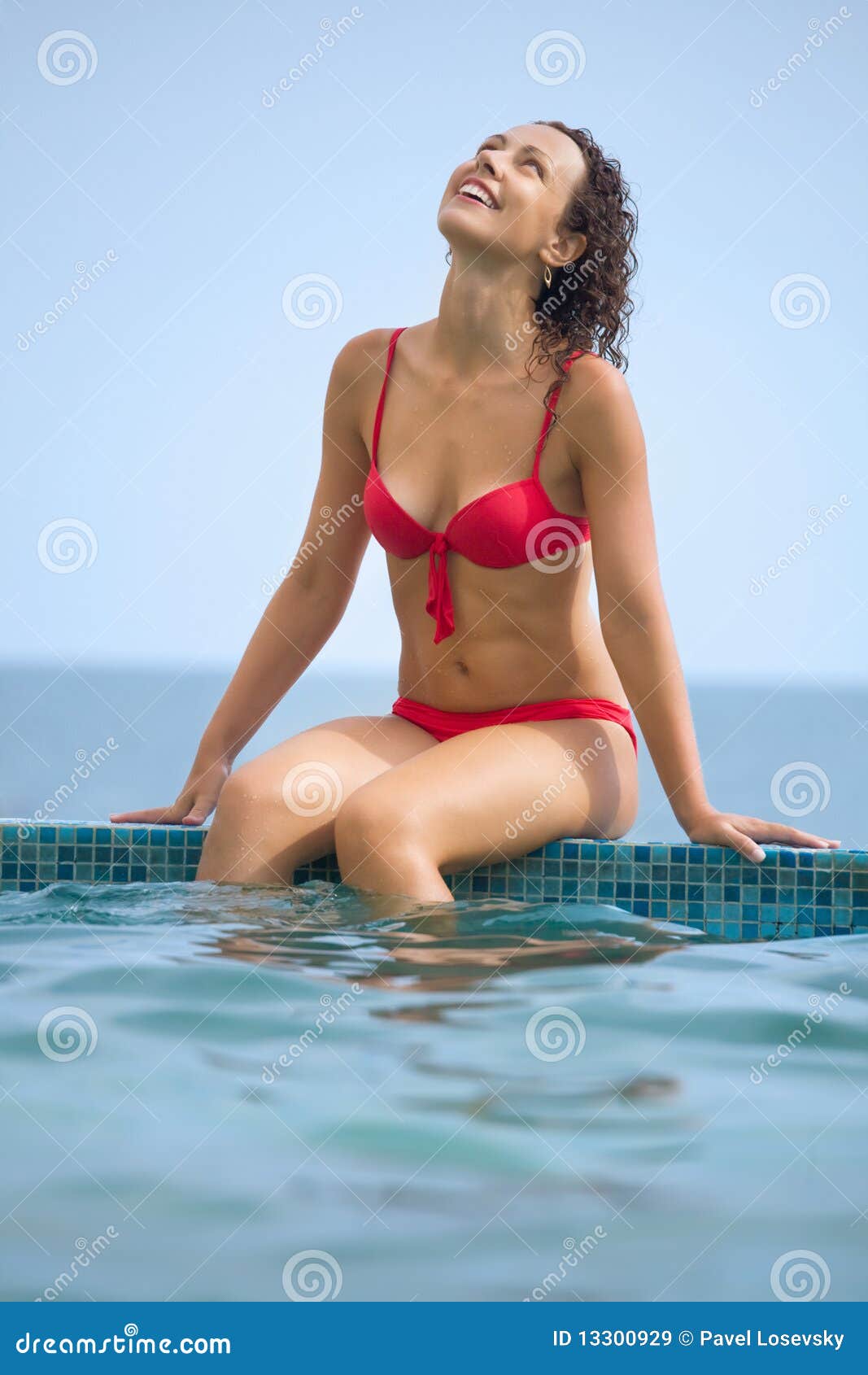 young beautiful sexual woman sitting on ledge pool