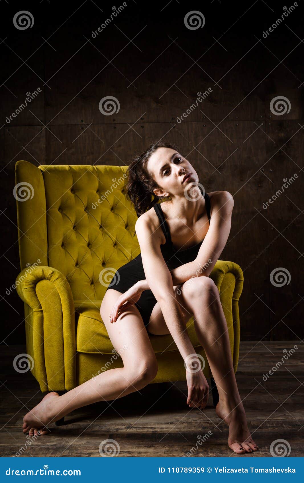 Young Beautiful, Caucasian Woman with a Thin Figure and Long Bare Legs, Barefoot Posing Sitting on a Yellow Chair in the Inte Stock Image