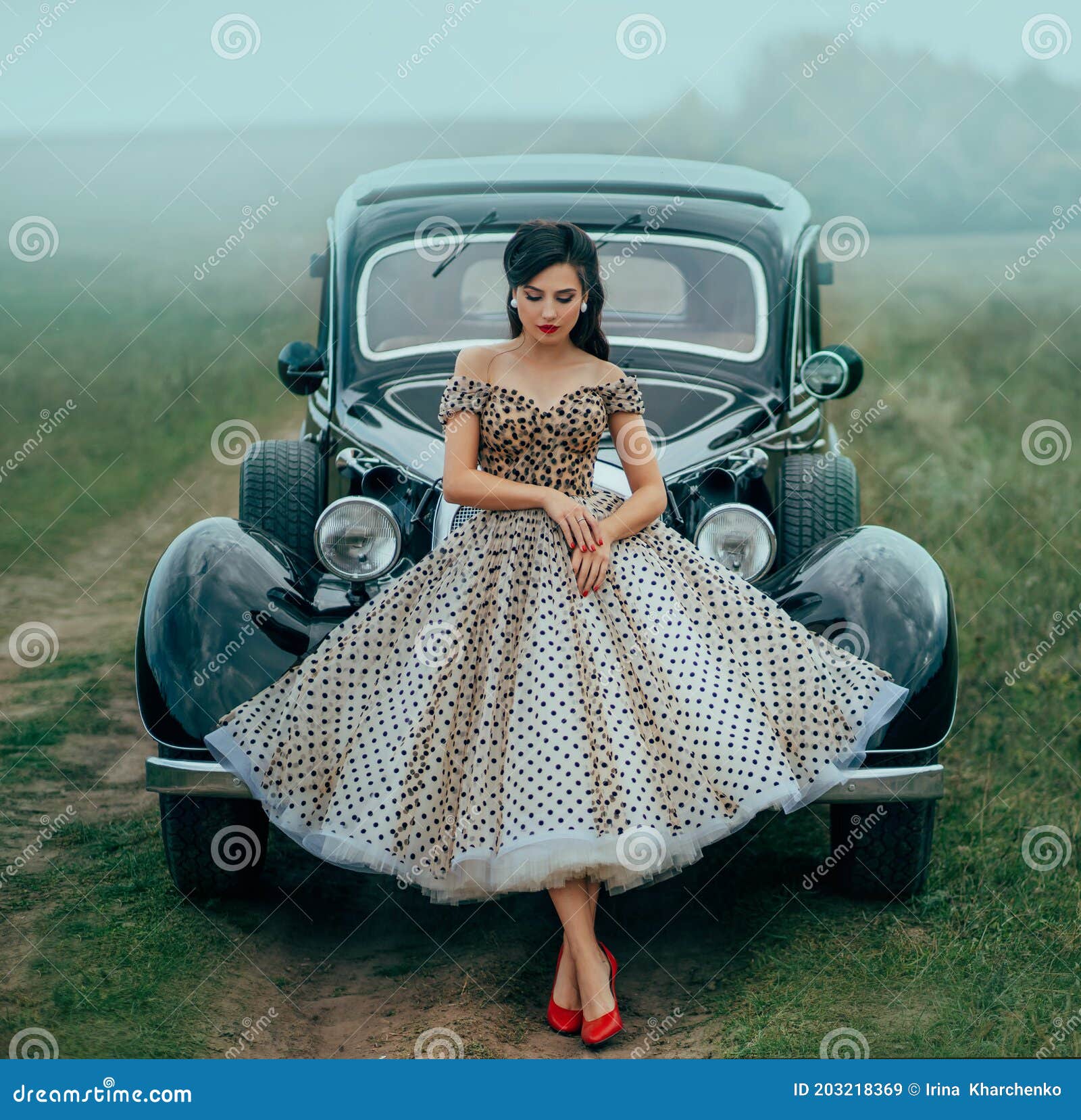 young beautiful sexy woman in pin-up style clothes posing near black retro car. polka dot white dress, vintage hairstyle