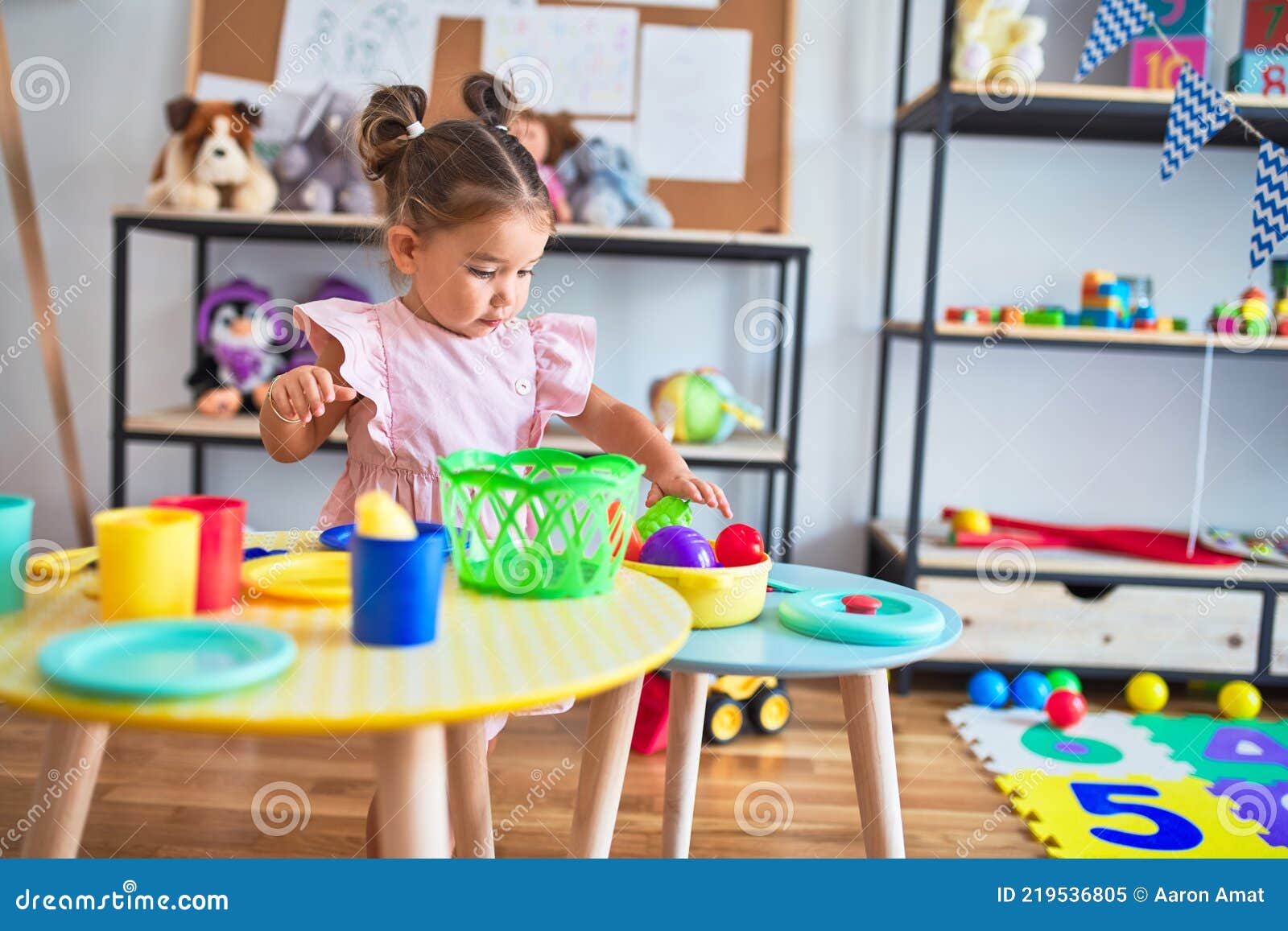 young beautiful toddler playing with cutlery and food toys on the table at kindergaten