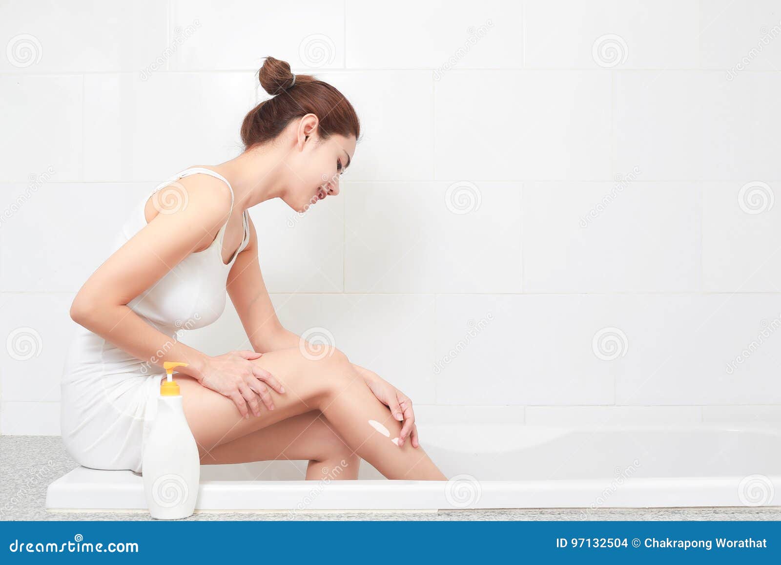 young beautiful woman applying body lotion on her attractive leg