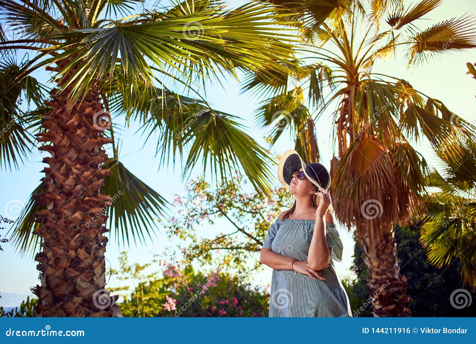 Young woman lying in hammock under palm tree on beach 