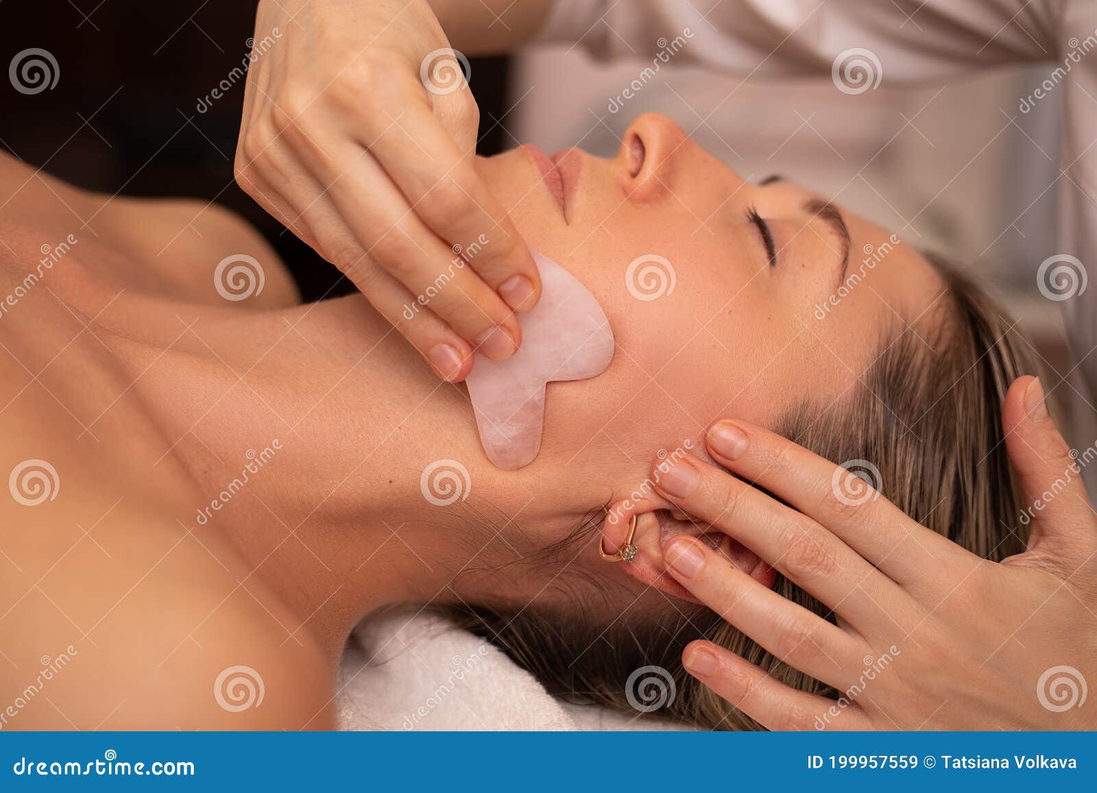 young and beautiful woman during chinese traditional massage - gua sha. close-up photo. beauty treatment in spa salon. anti-aging
