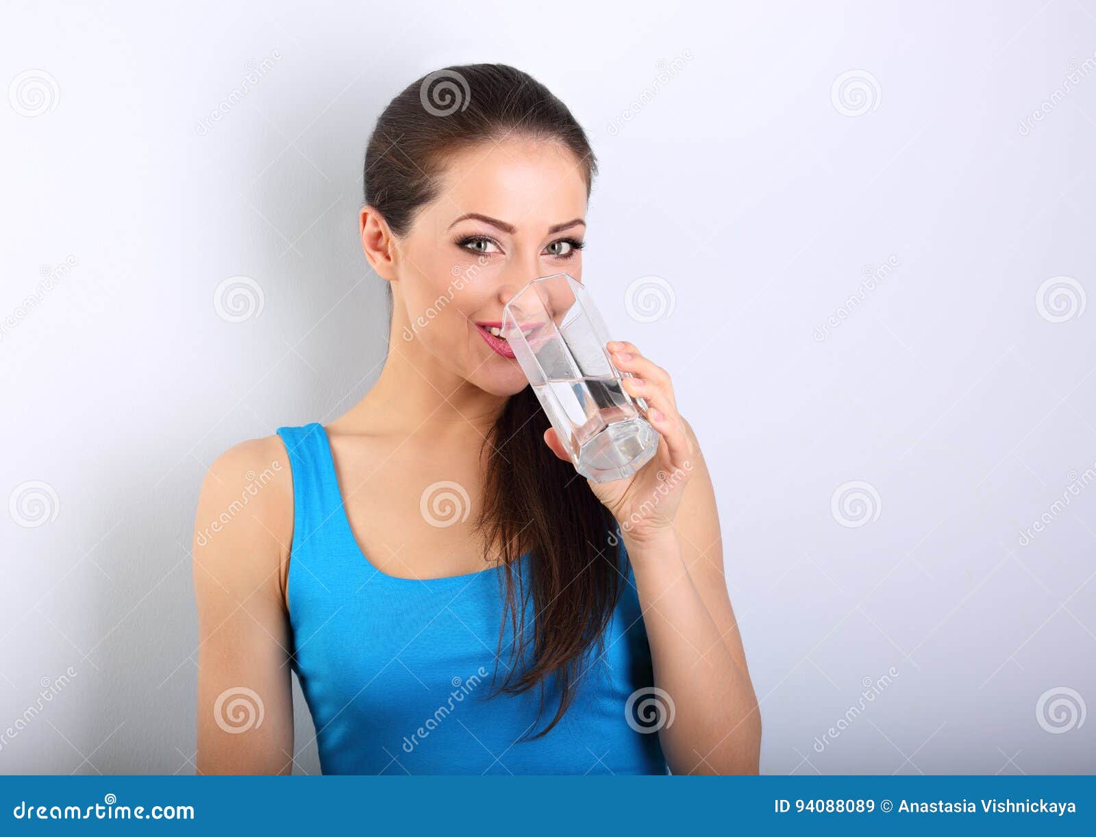 young beautiful woman drinking fresh pure water from glass on bl