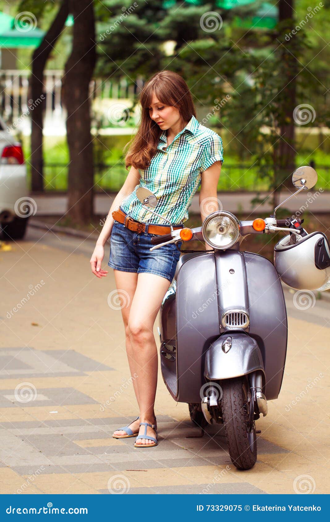 young beautiful woman poses near scooter city park summe rear view 73329075