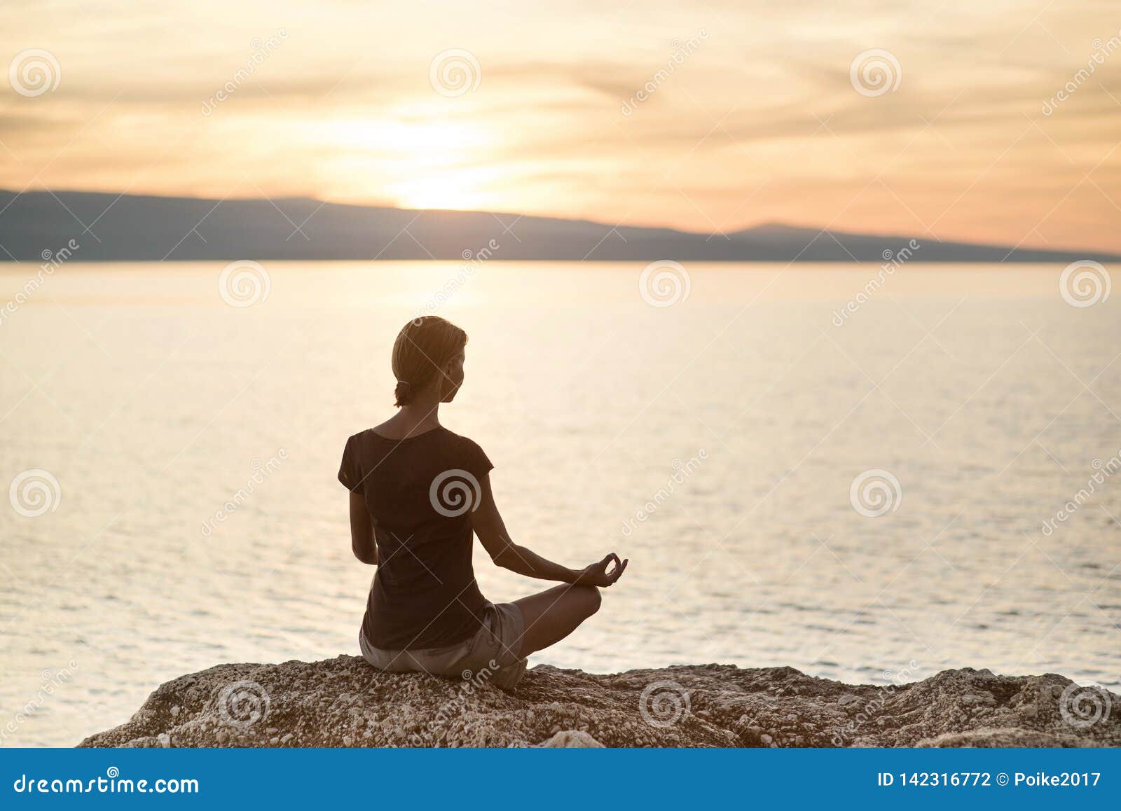 young woman practicing yoga near the sea at sunset. harmony, meditation and travel concept. healthy lifestyle