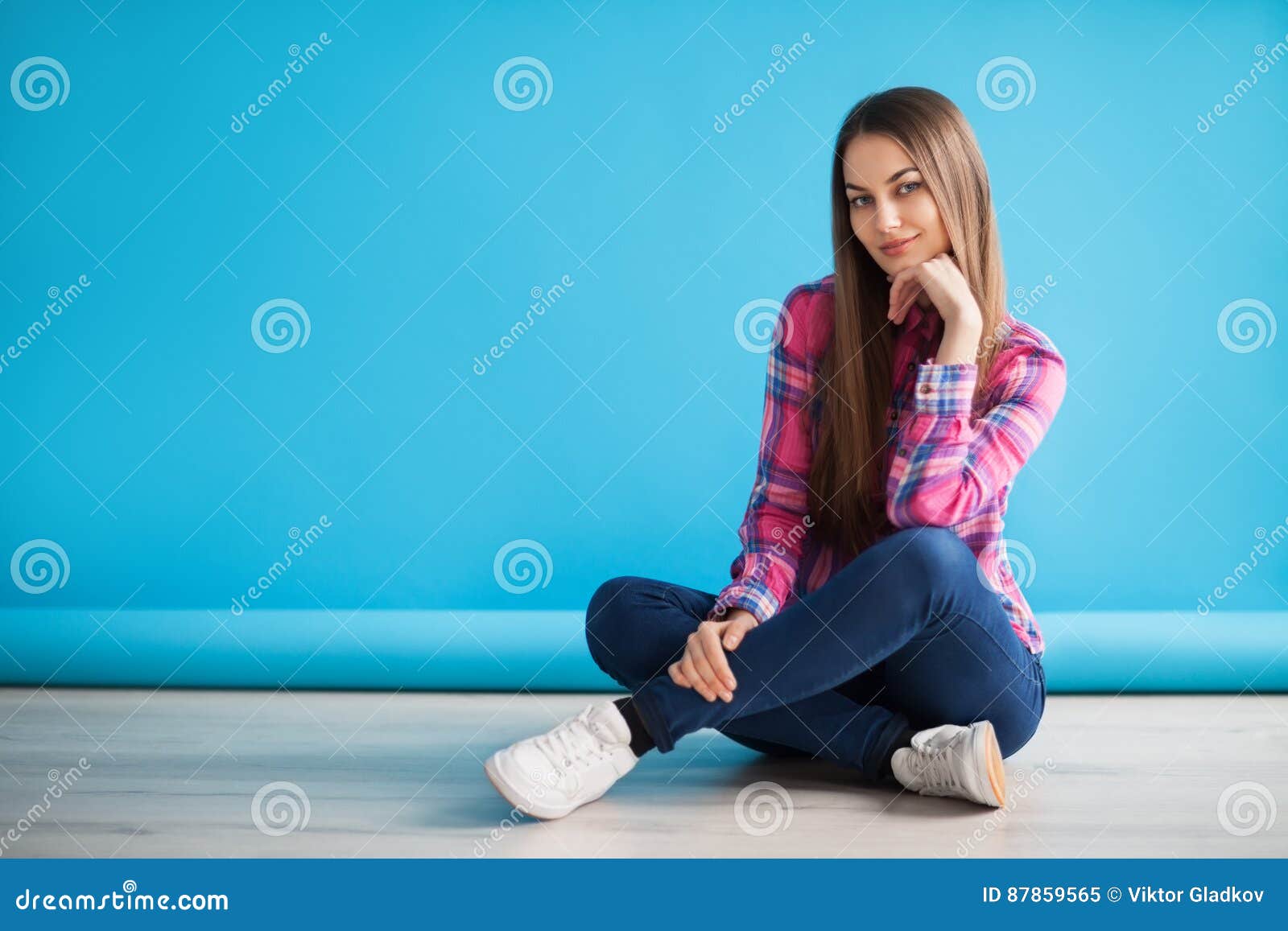 Young Beautiful Woman Sitting on the Floor on Blue Background Stock ...