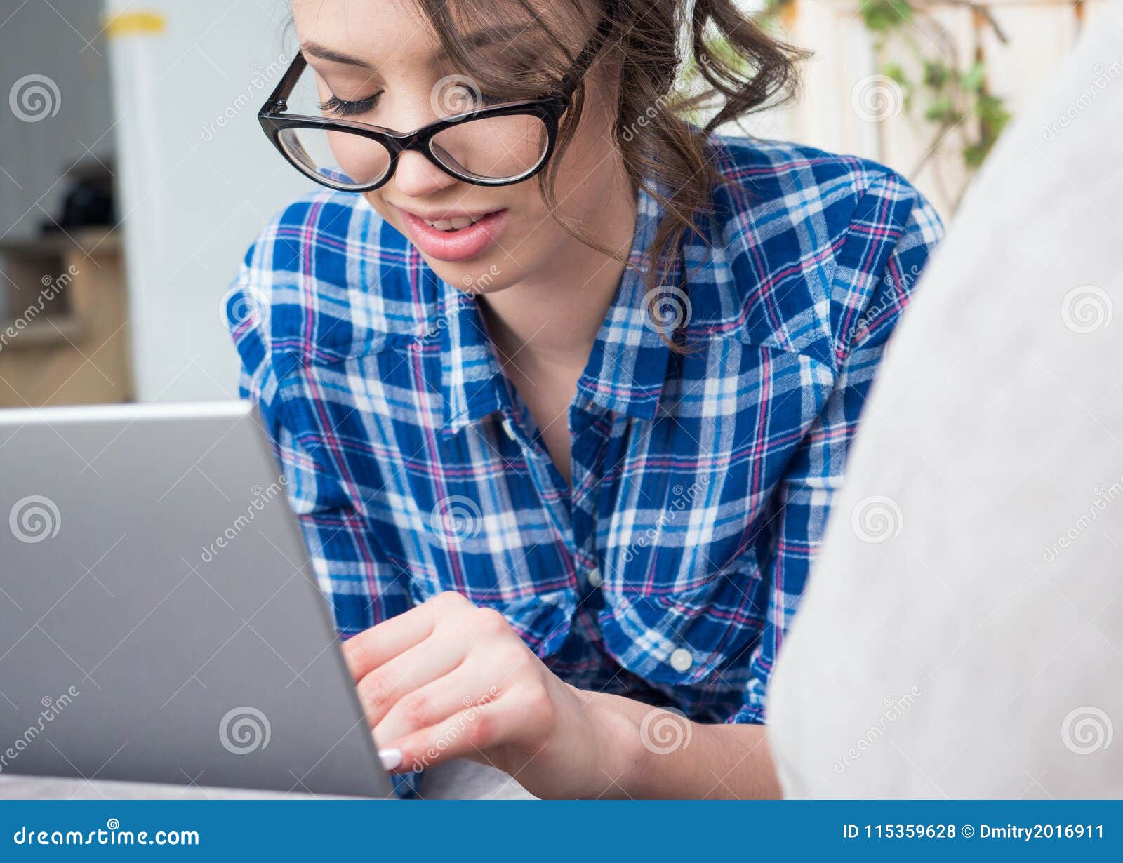 Young Beautiful Woman in Eyeglasses Using a Laptop Computer at Home
