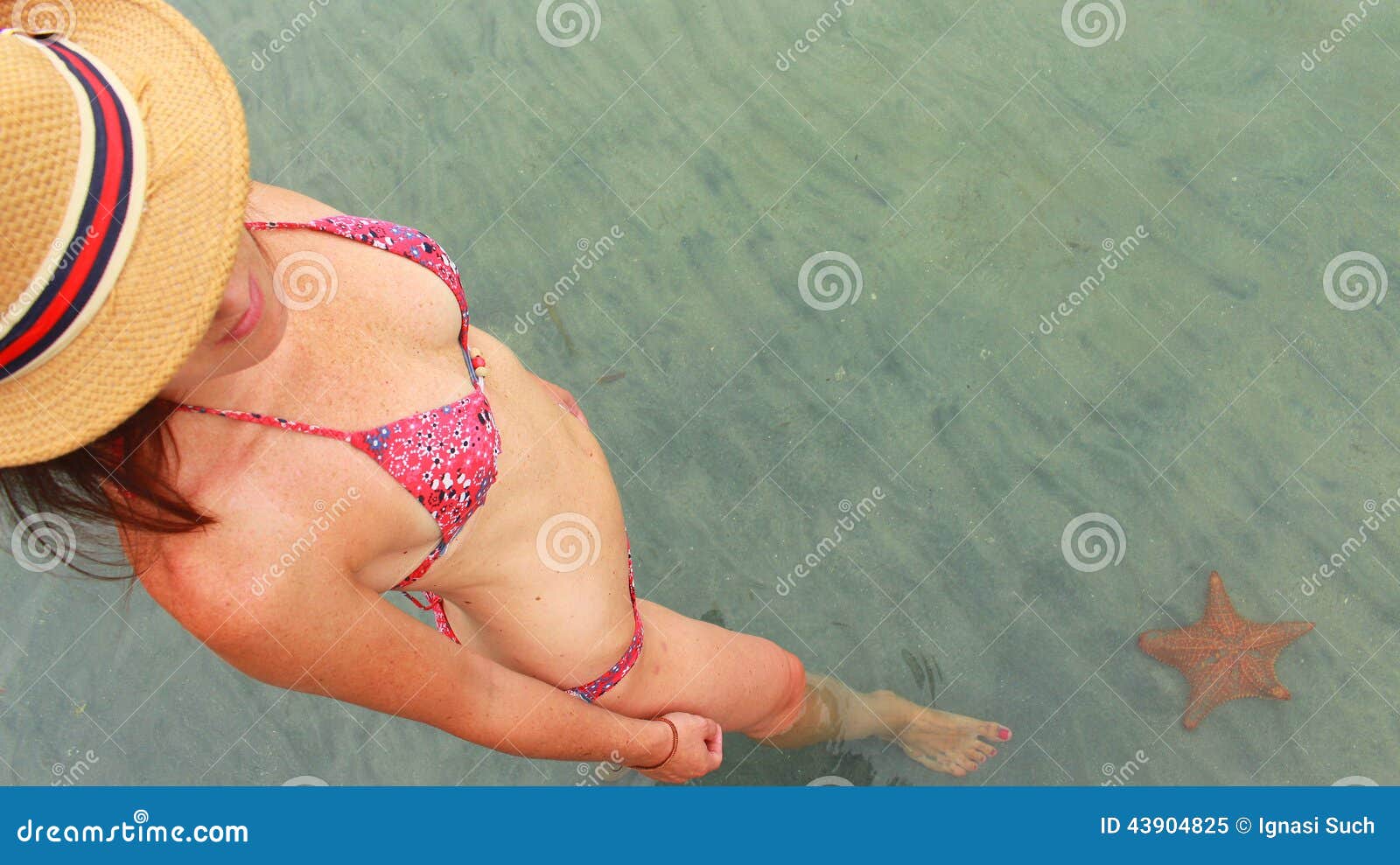 young beautiful woman watching a starfish in playa estrella, panama