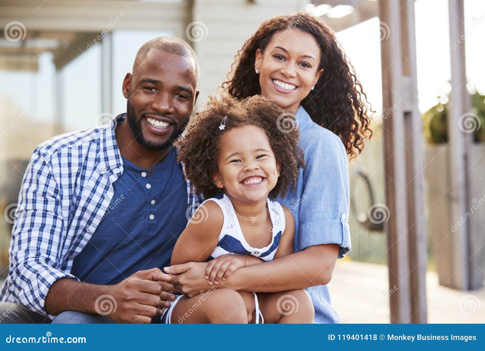 young black family embracing outdoors and smiling at camera