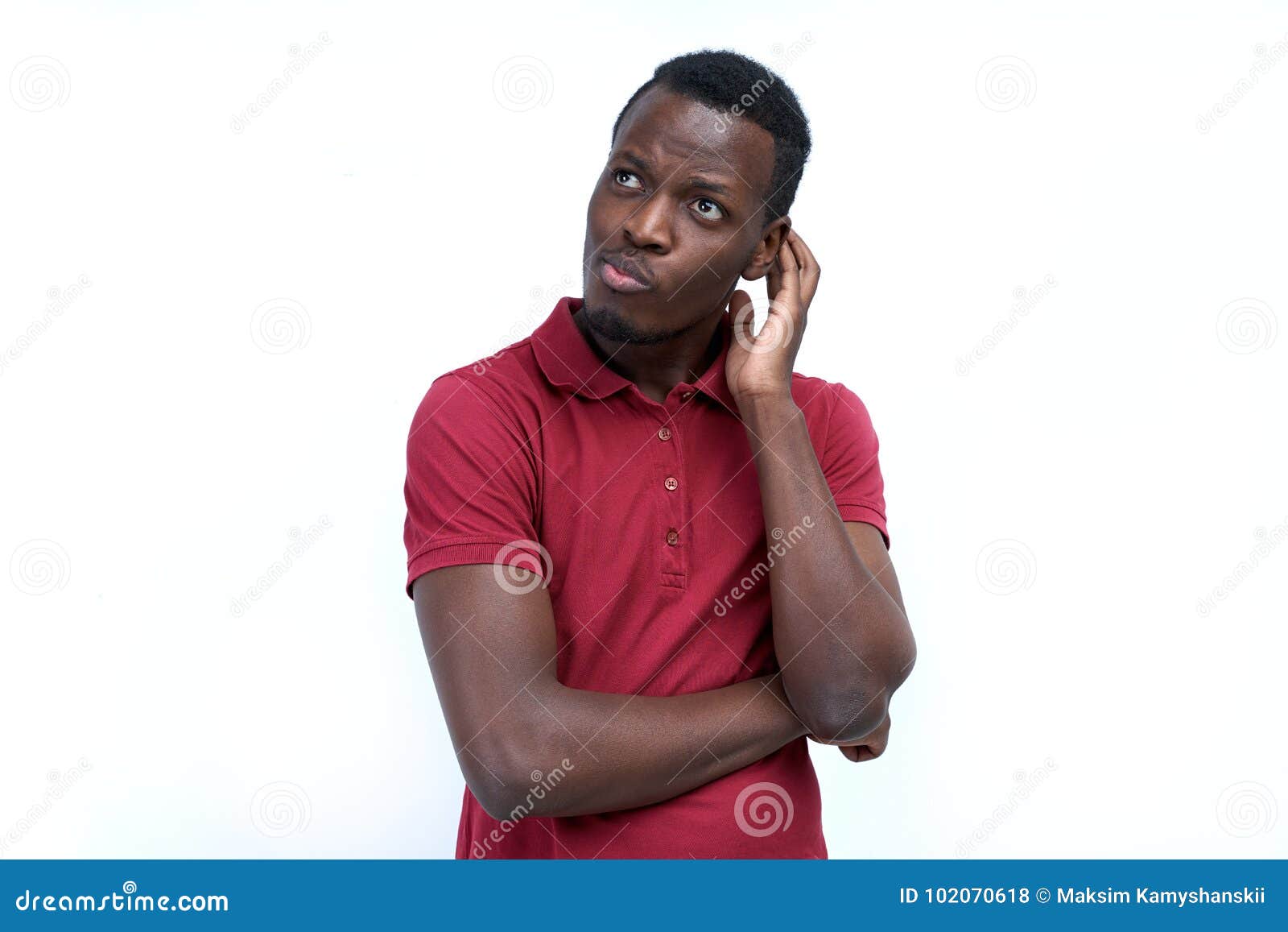 a young black man with a thoughtful expression, scratching his h