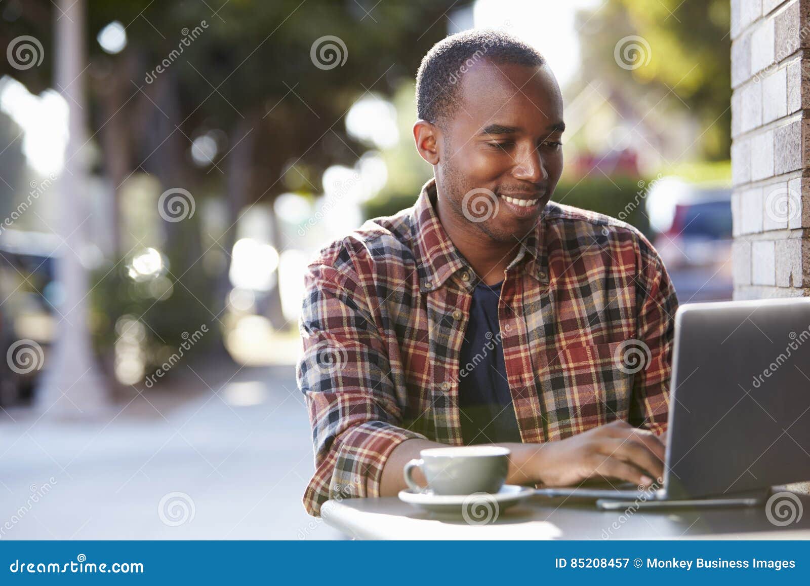 young black man using a laptop computer outside a cafe