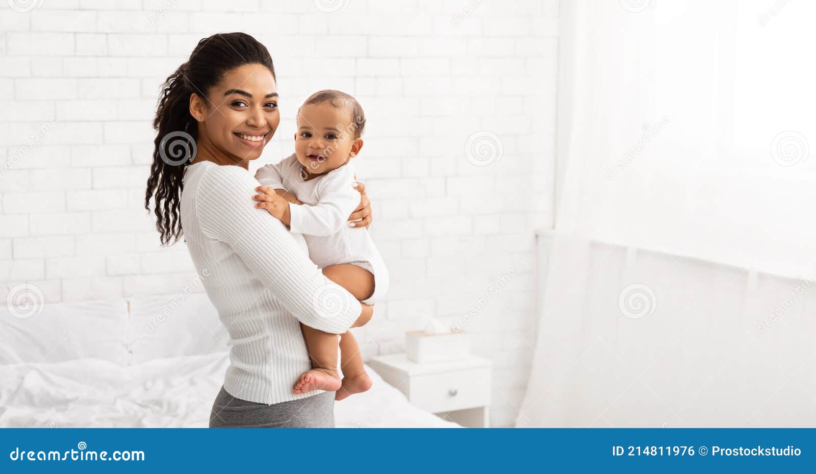 young black mom holding baby toddler posing standing indoors, panorama