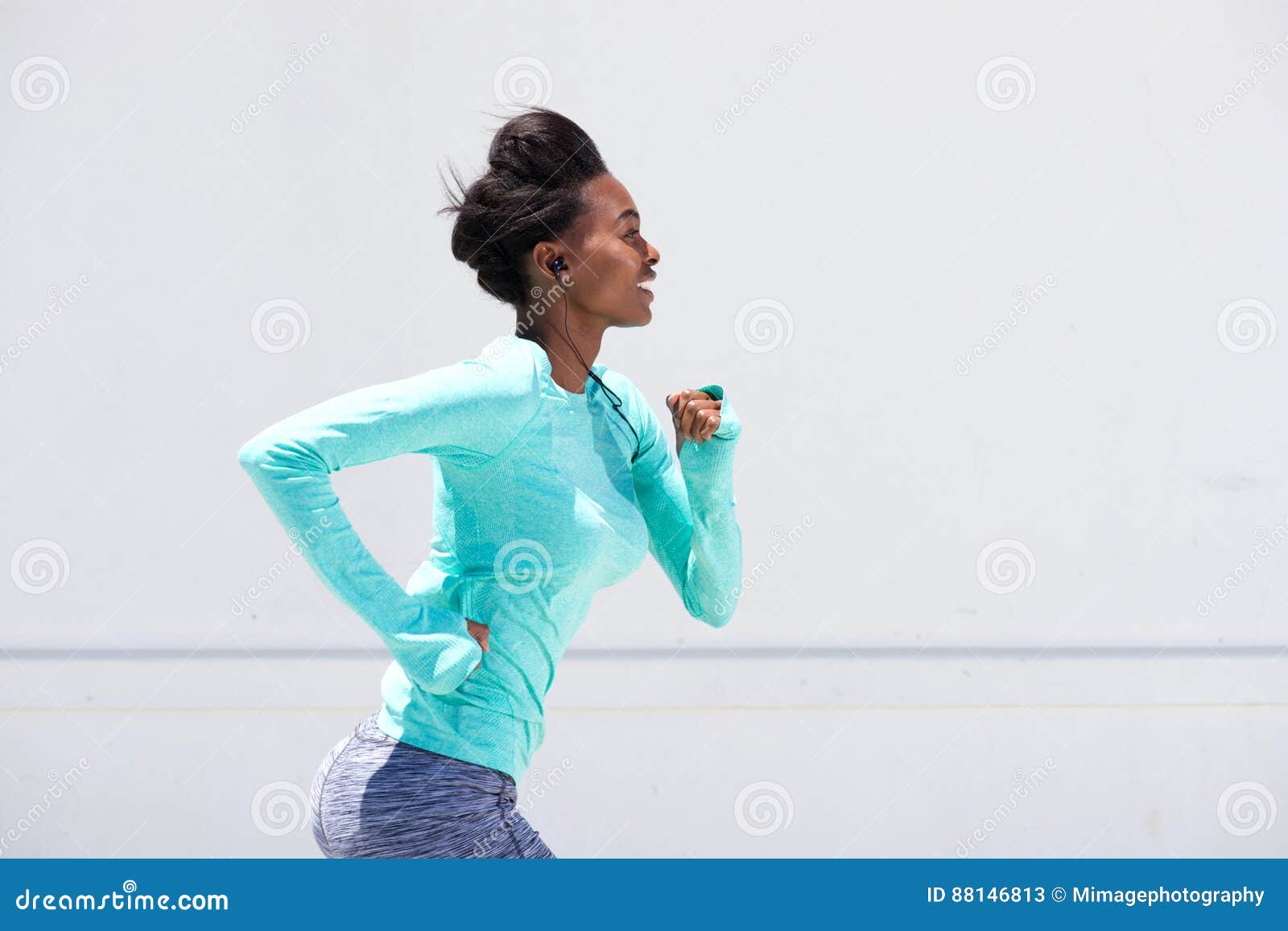 young black woman running outside with earphones