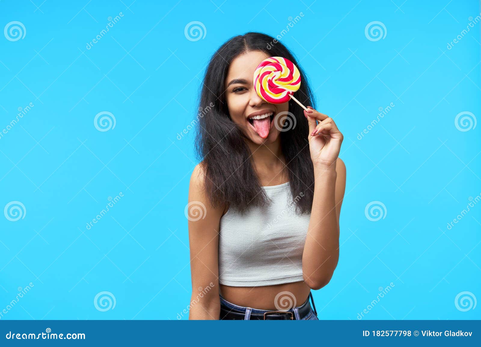 Young Black Woman Showing Tongue Covering Her Eye With Colo