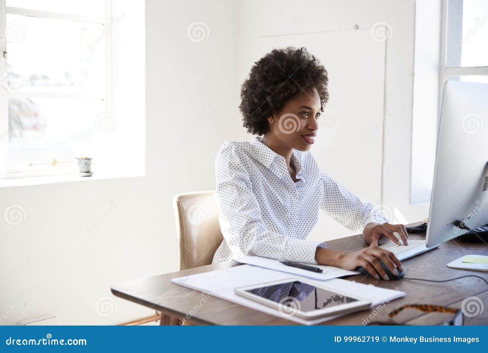 Young black business woman thinking at desk in office Stock Photo