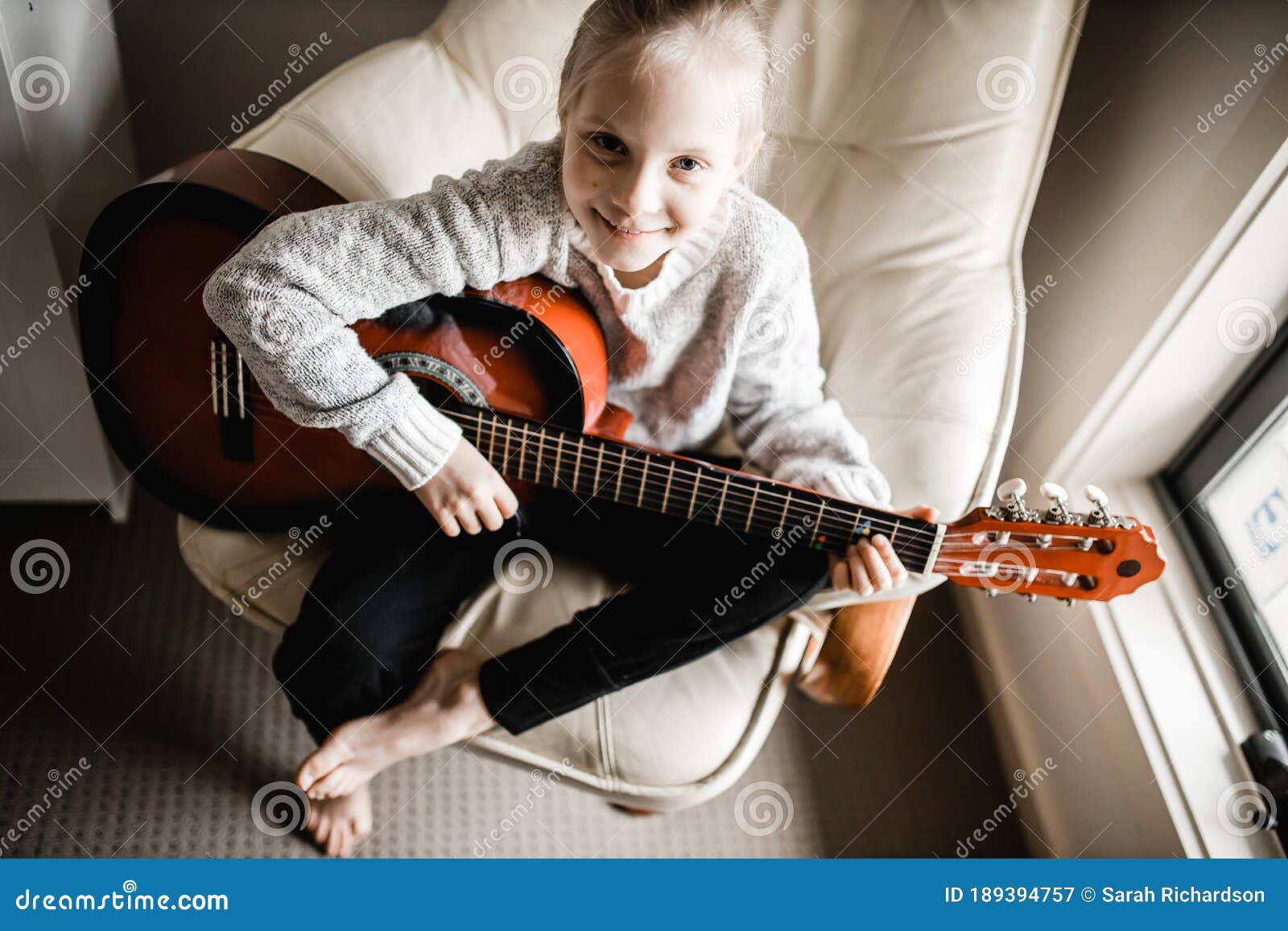 a young caucasion girl practicing playing her guitar