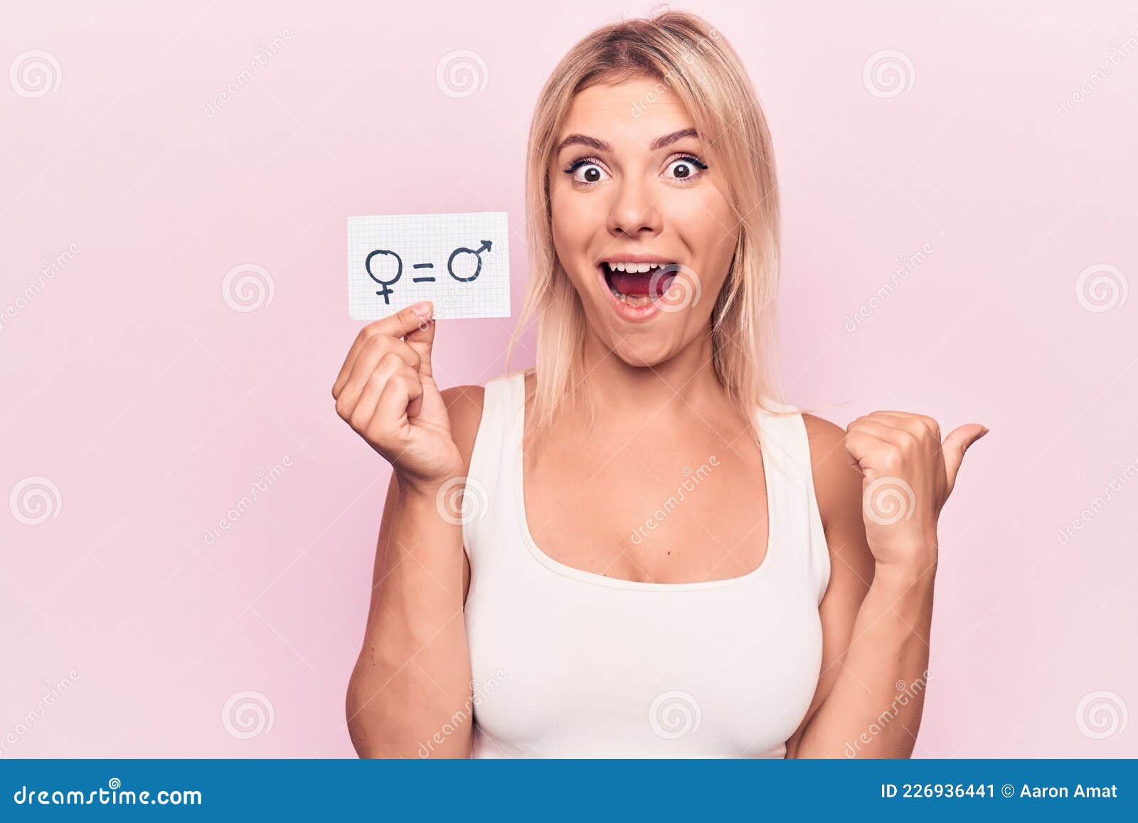 Young Blonde Woman Asking for Sex Discrimination Holding Paper with Gender Equality Message Pointing Thumb Up To the Side Smiling Stock Image Porn Pic Hd