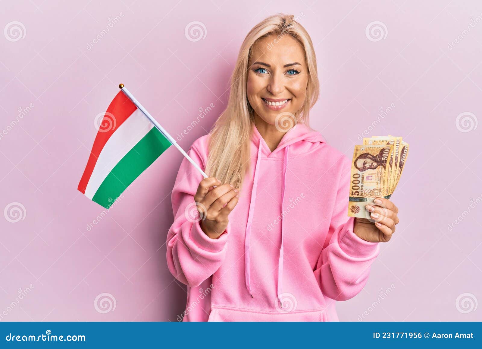 Young Blonde Woman Holding Hungary Flag And Forint Banknotes Smiling With A Happy And Cool Smile