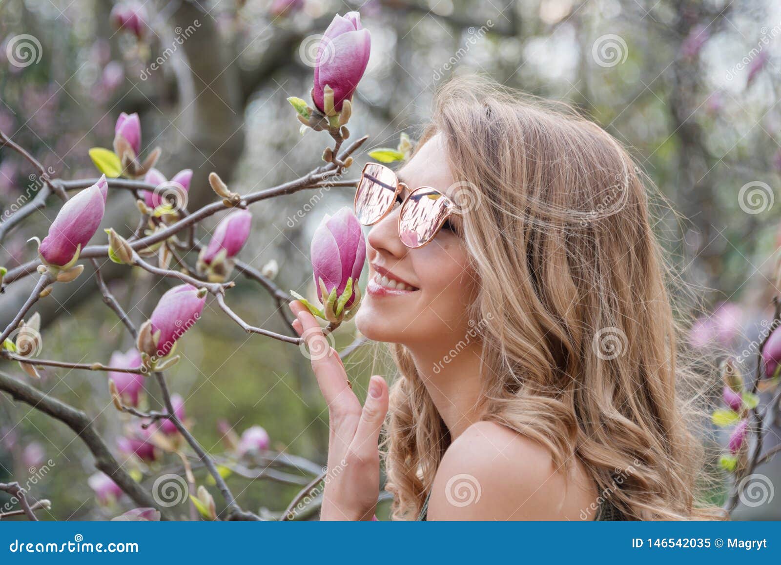 Young Blonde Woman Near Blossoming Magnolia Flowers Tree In Spring Park On Sunny Day Magnolia