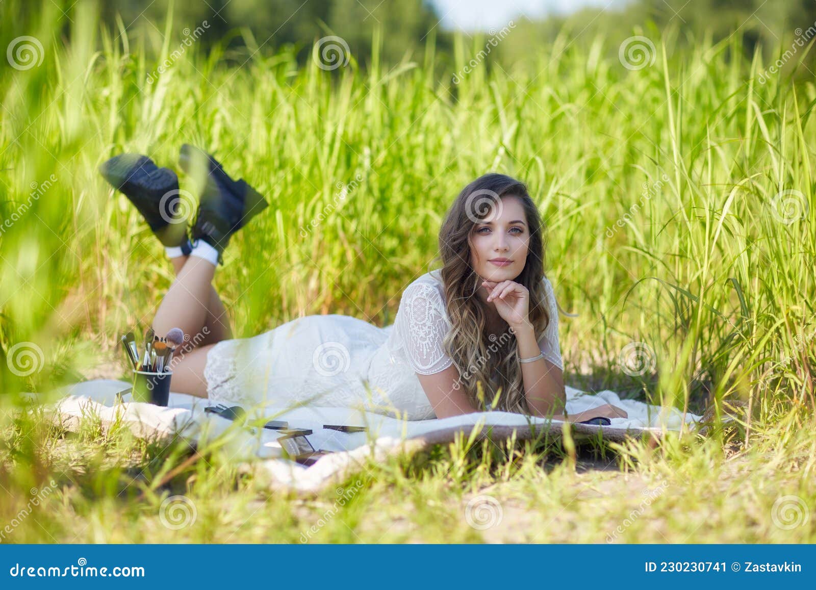 Young Blonde Woman in White Dress Lies on a Picnic Sheet in Tall Grass ...