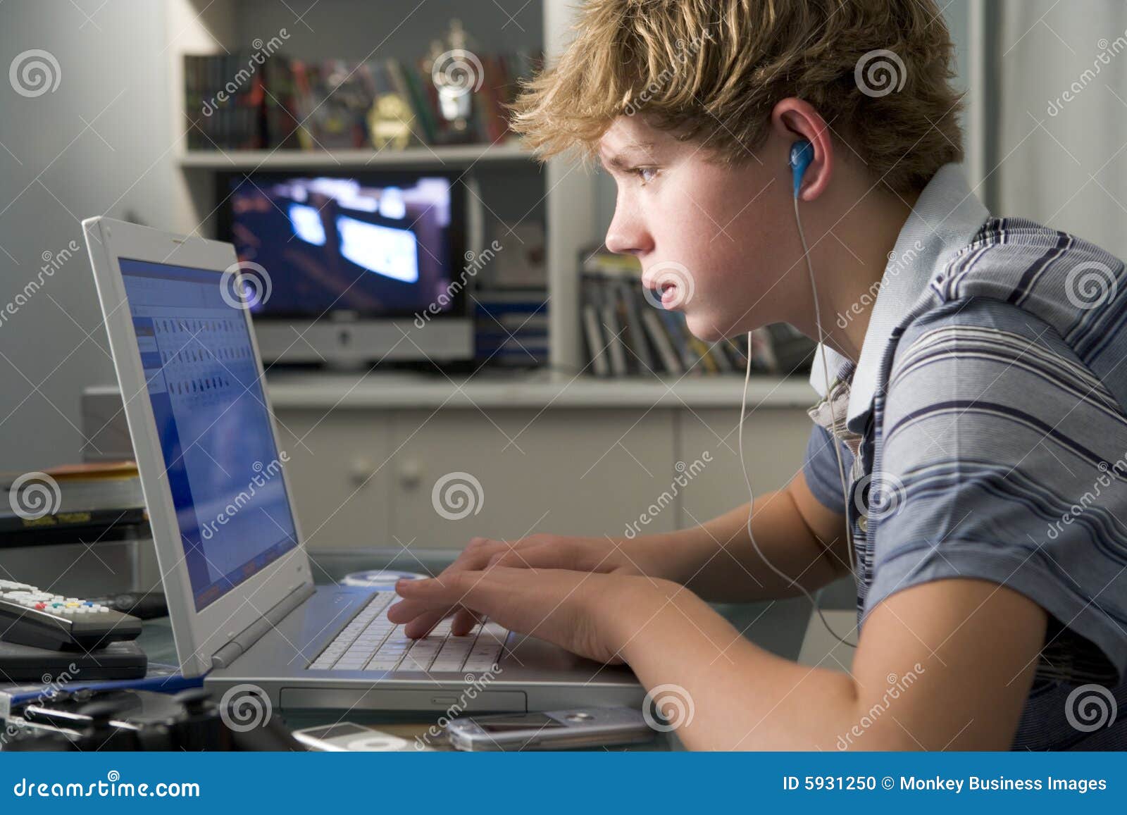 young boy in bedroom using laptop listening to mp3