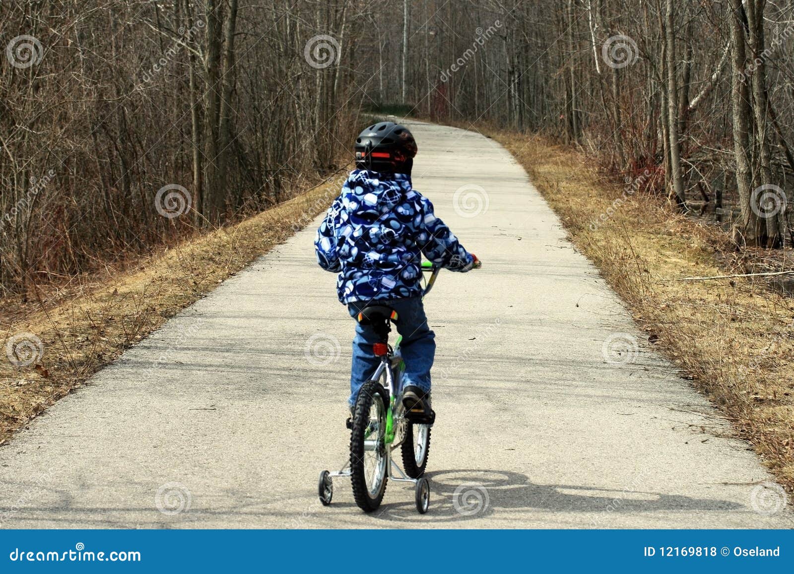 Young Boy on Bicycle with Training Wheels Learning To Ride Bike. Stock