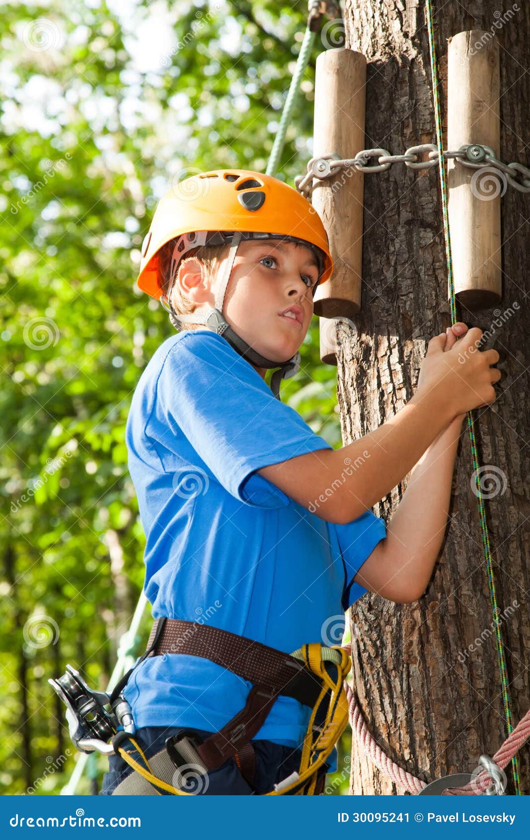 boy with climber equipment intently keeps rope