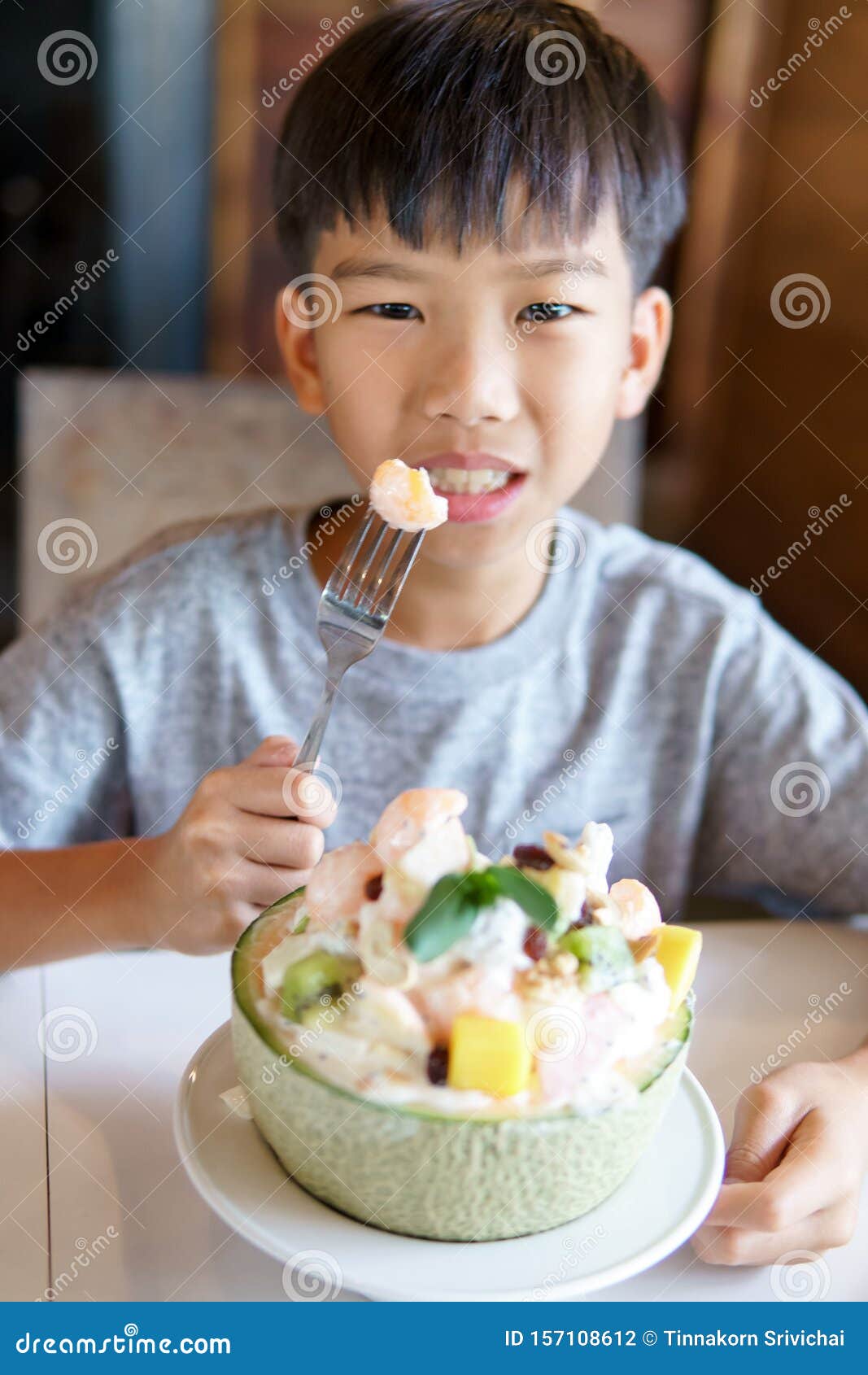Young boy eat melon salad stock photo. Image of eating 157108612