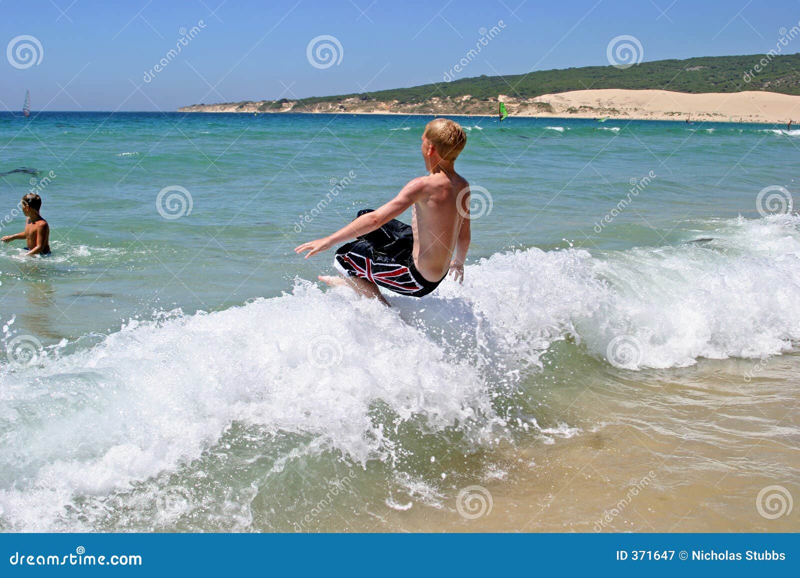 young boy jumping into wave on a sunny beach