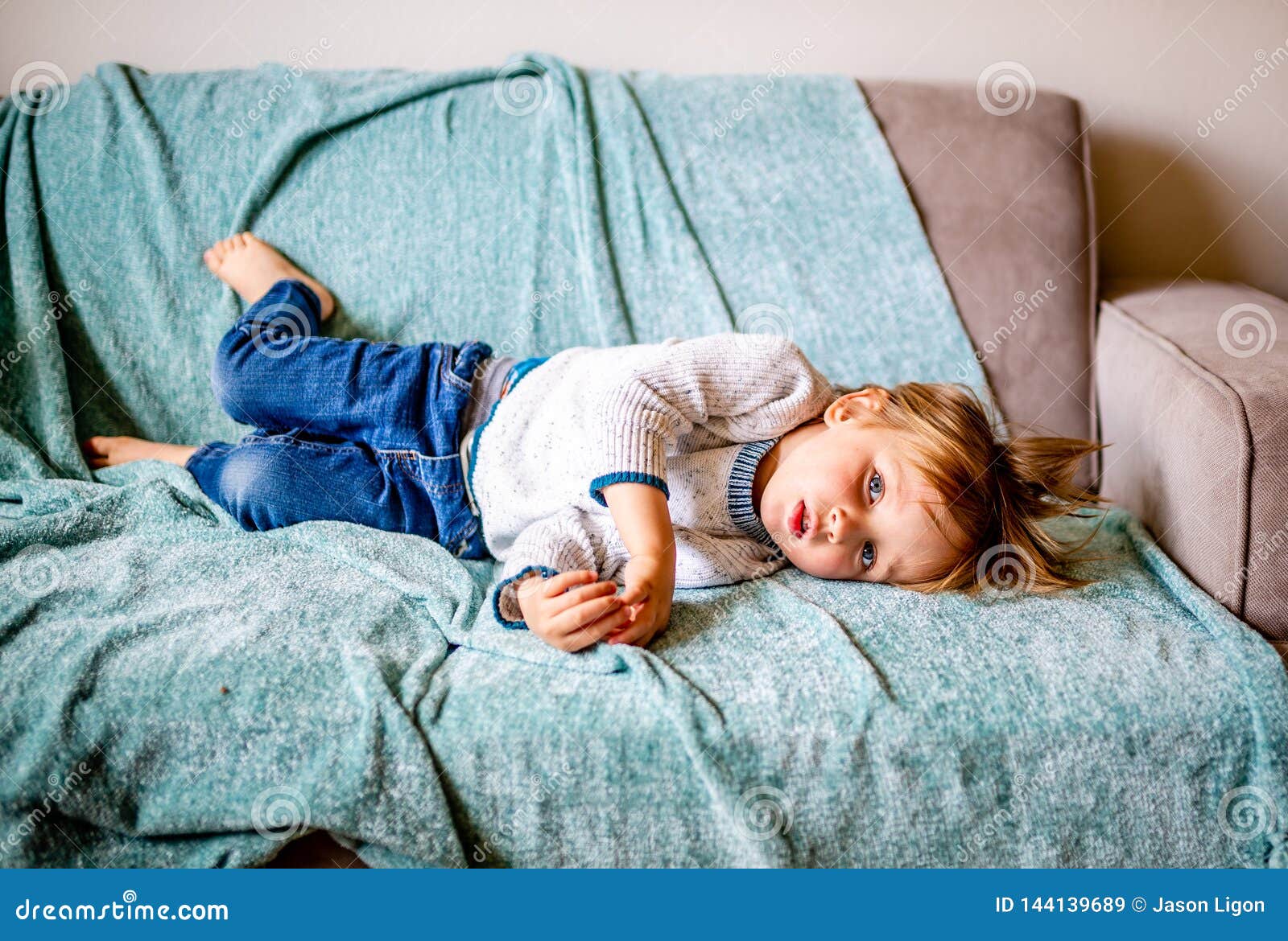 young boy lays on couch
