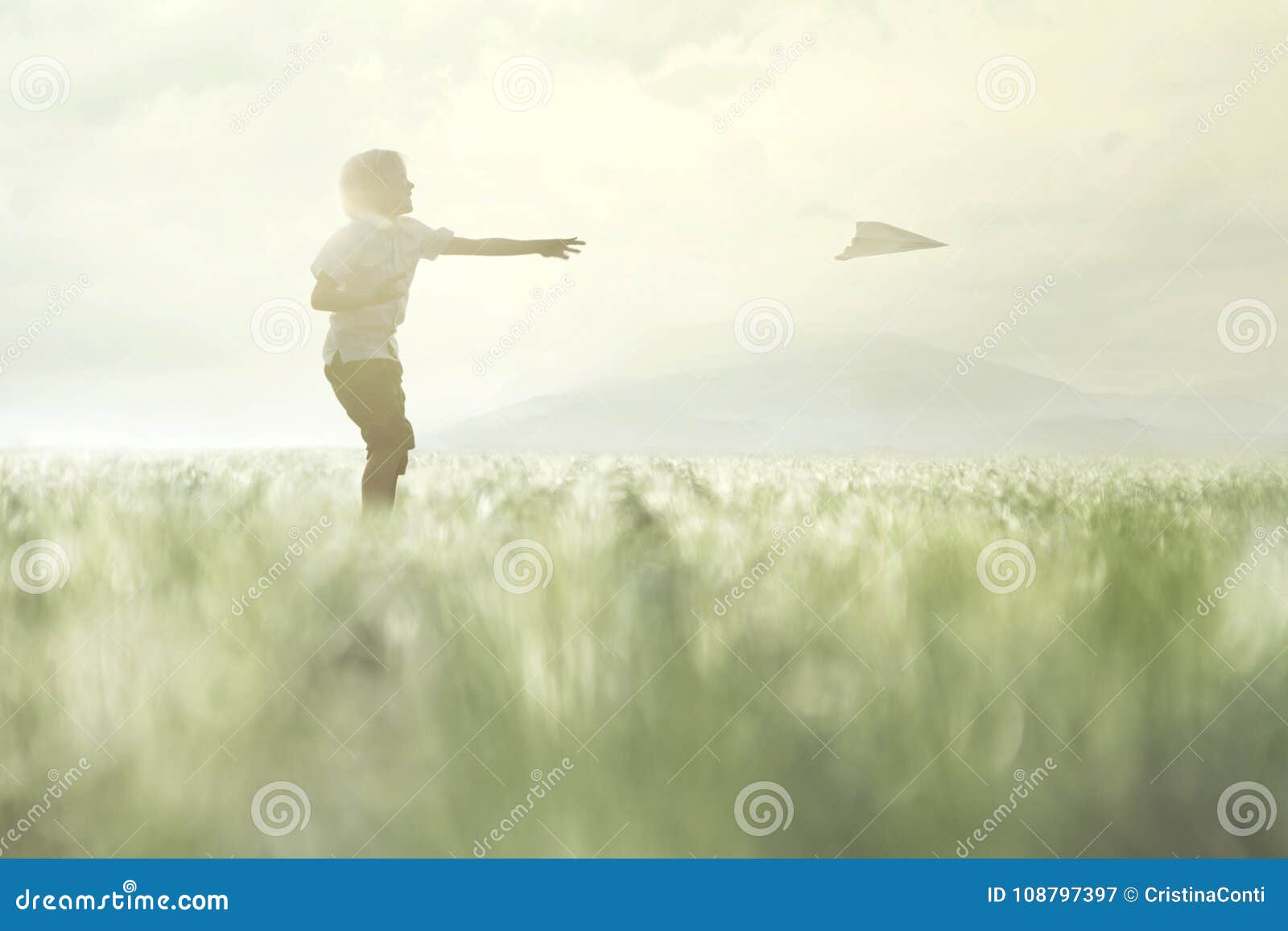 young boy makes his paper airplane fly in a meadow