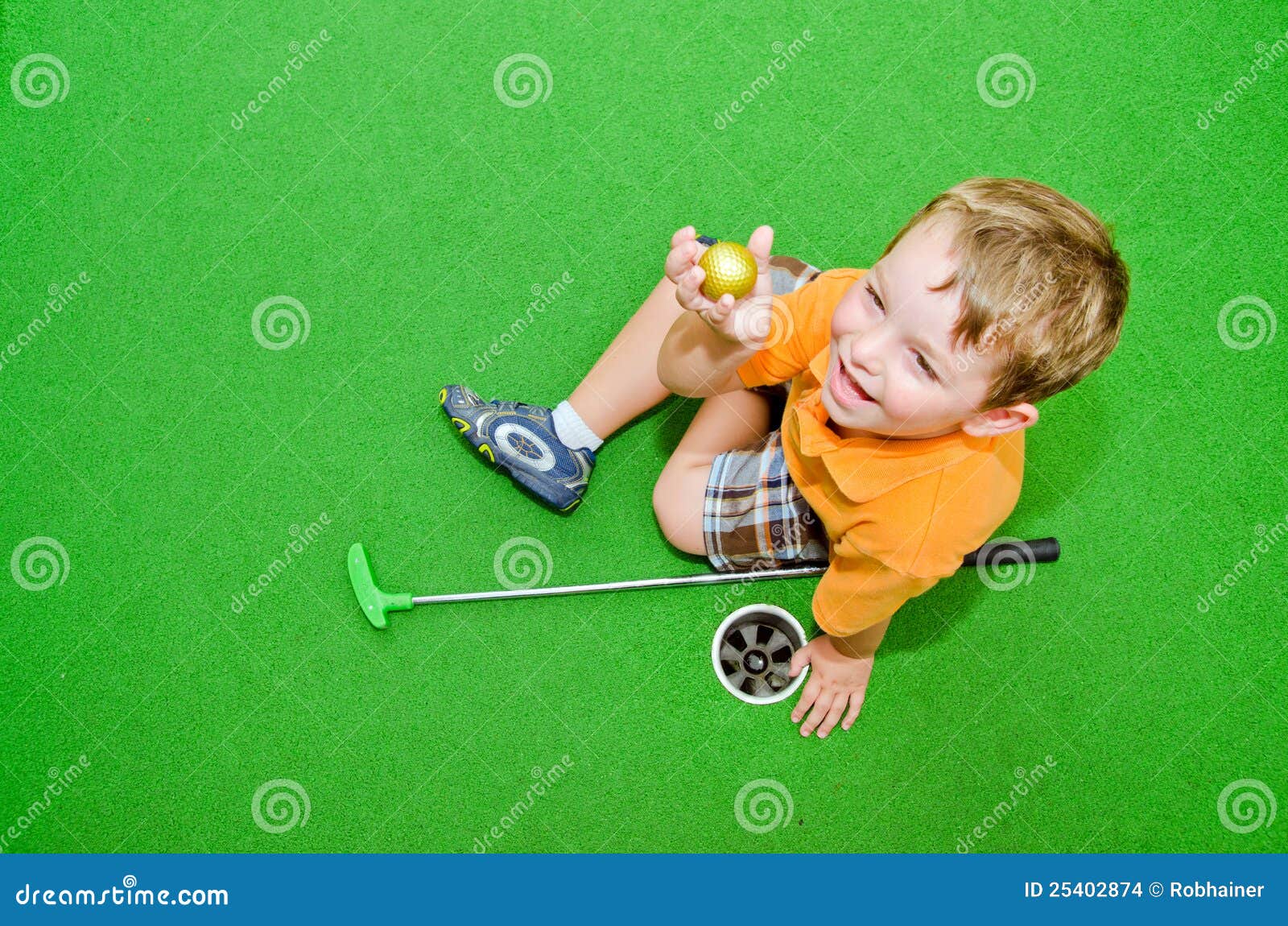 young boy plays mini golf