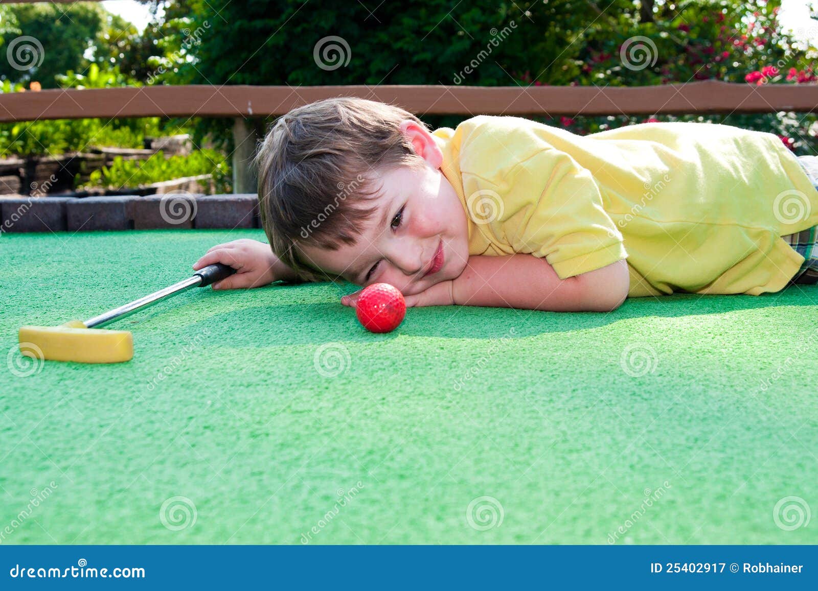 young boy plays mini golf