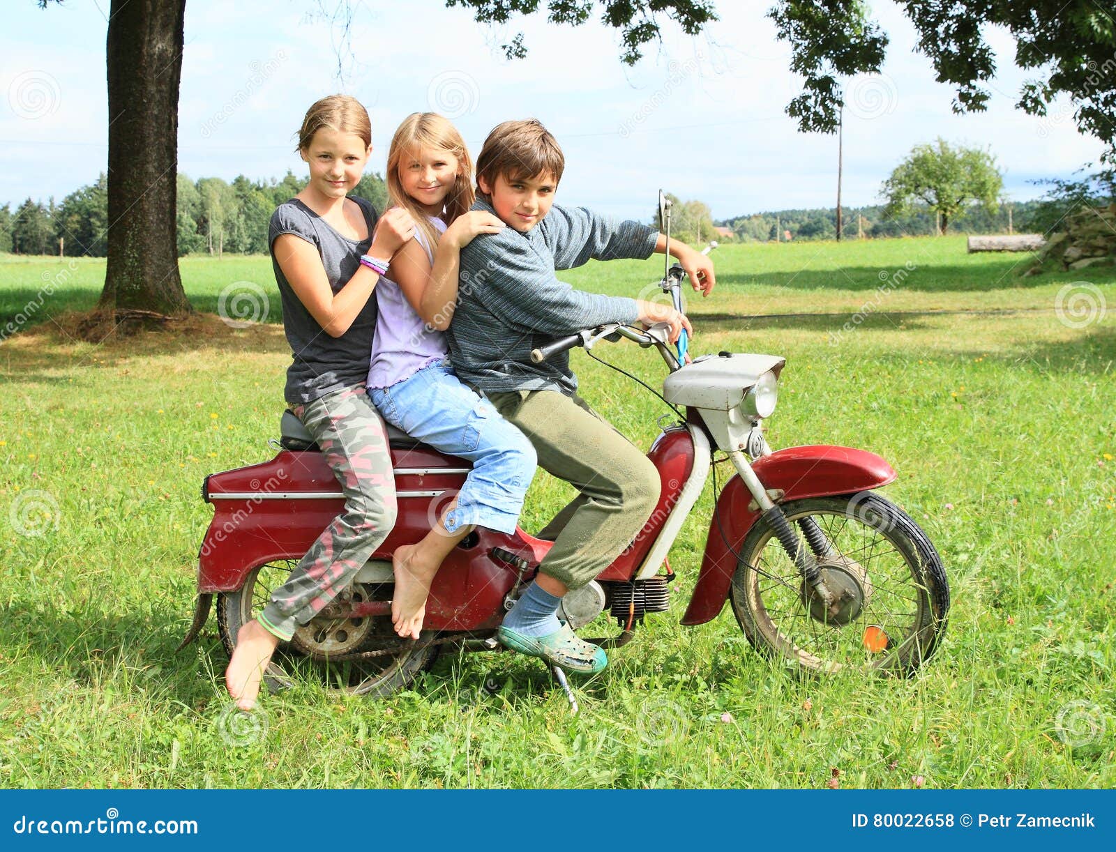 https://thumbs.dreamstime.com/z/young-boy-riding-motorbike-kid-old-red-two-barefoot-little-girls-as-passengers-green-grass-meadow-80022658.jpg