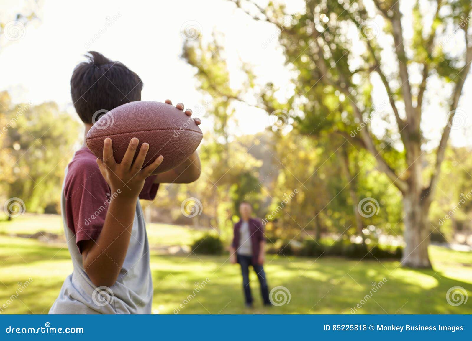 young boy throwing ball to dad in park, focus on foreground