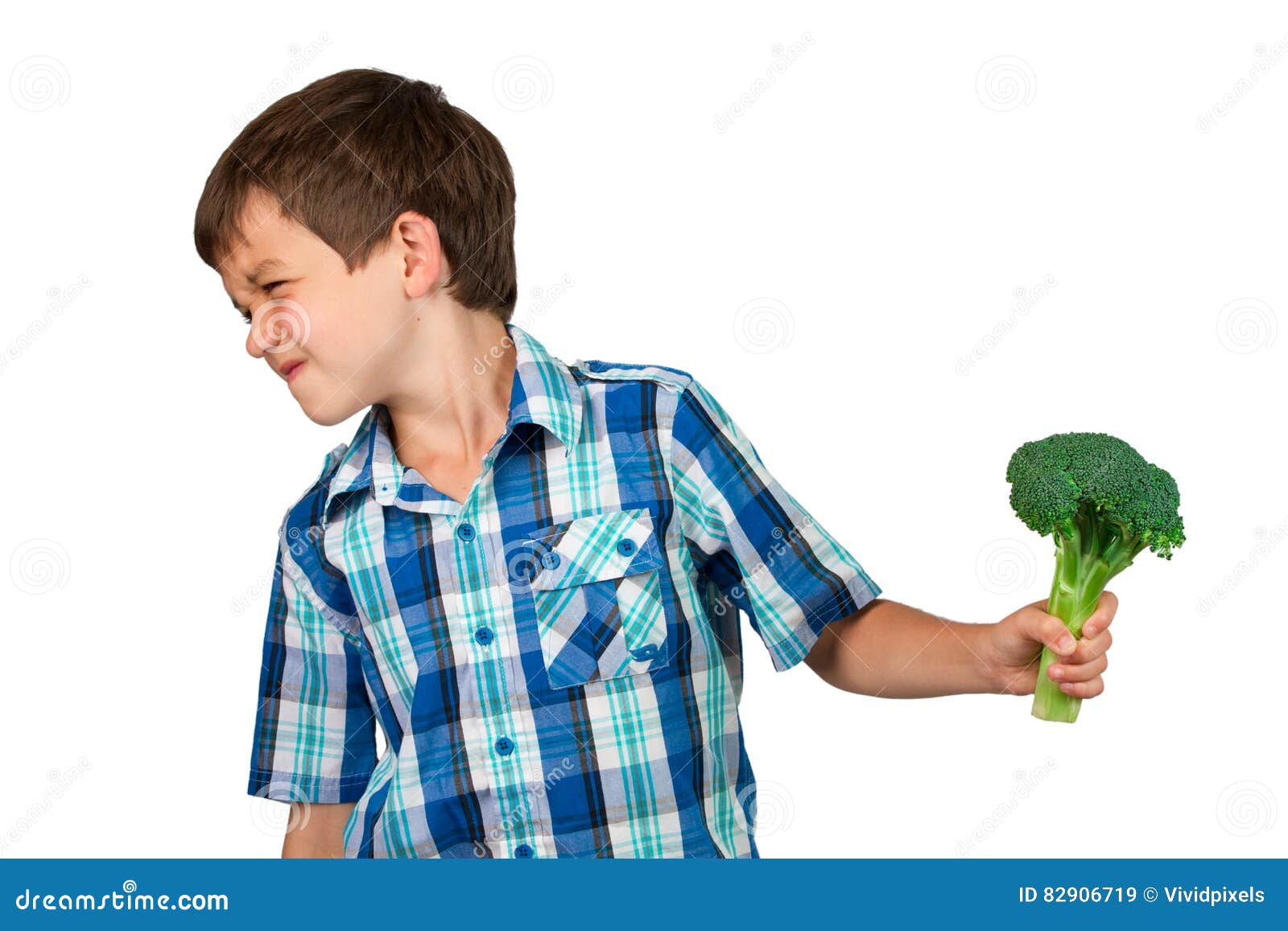 Young Boy Turning His Head Away from a Broccoli Bunch Stock Image