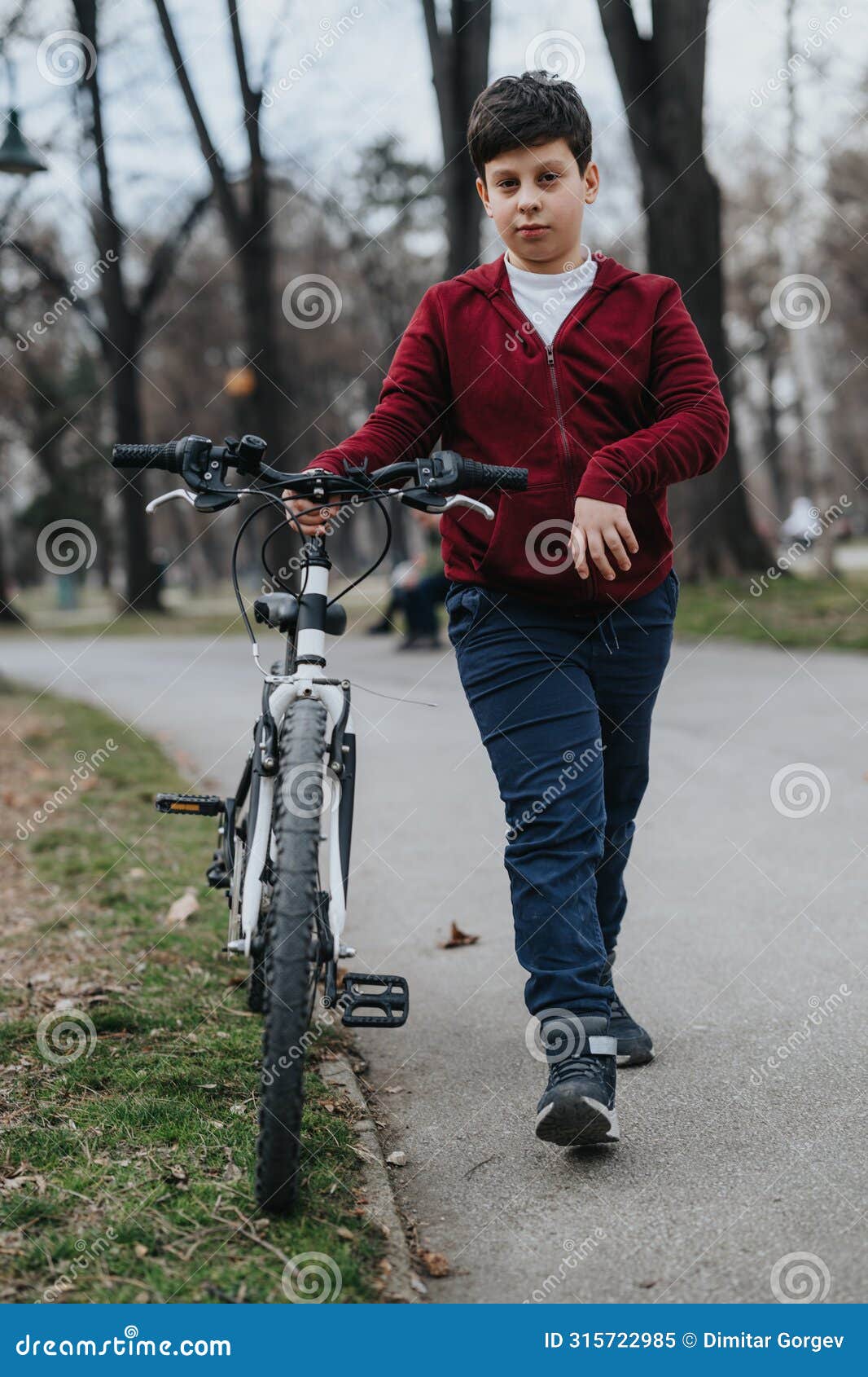 young boy walking with his bicycle in the park, enjoying an active day outdoors