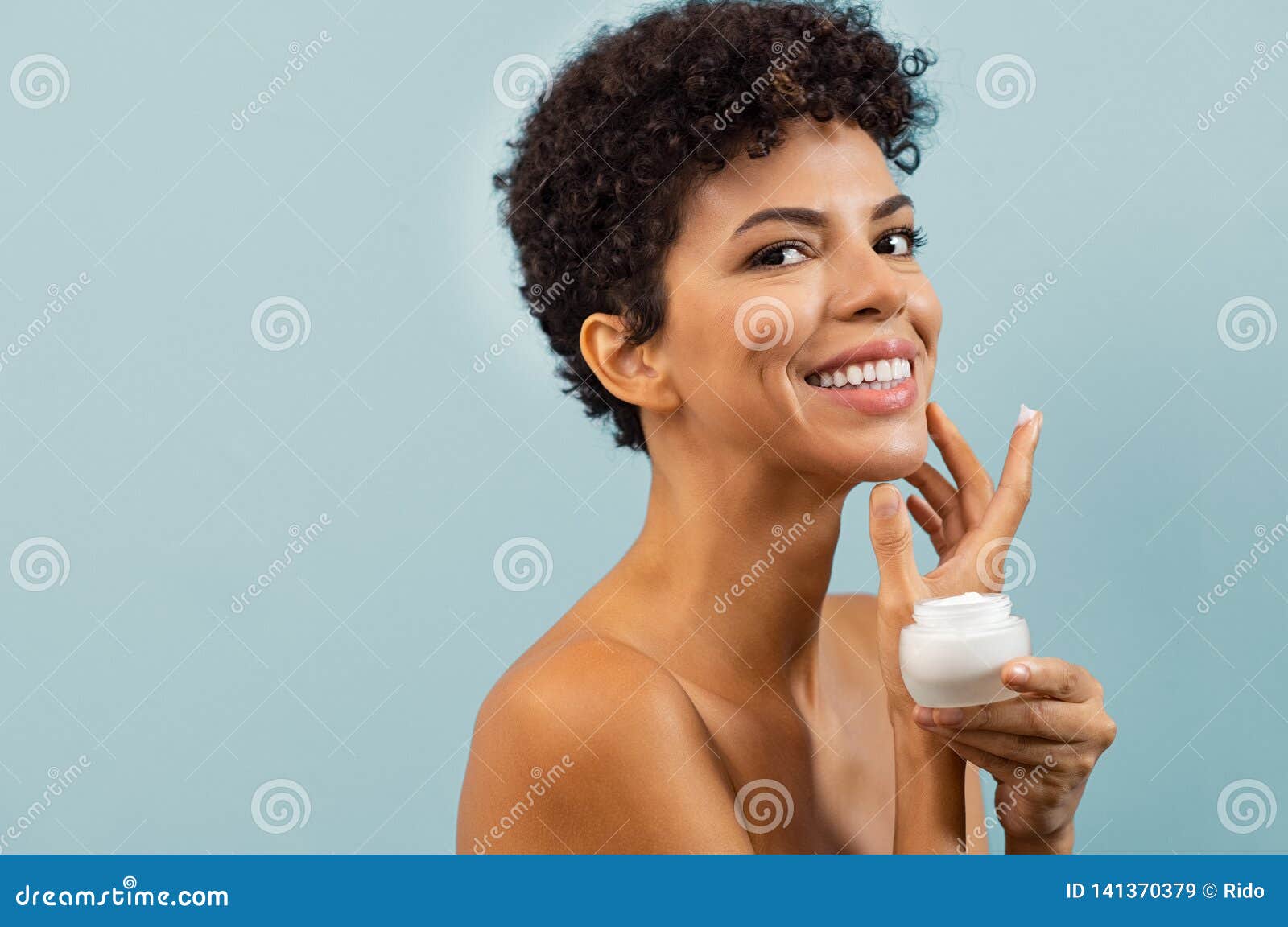 young brazilian woman applying moisturizer