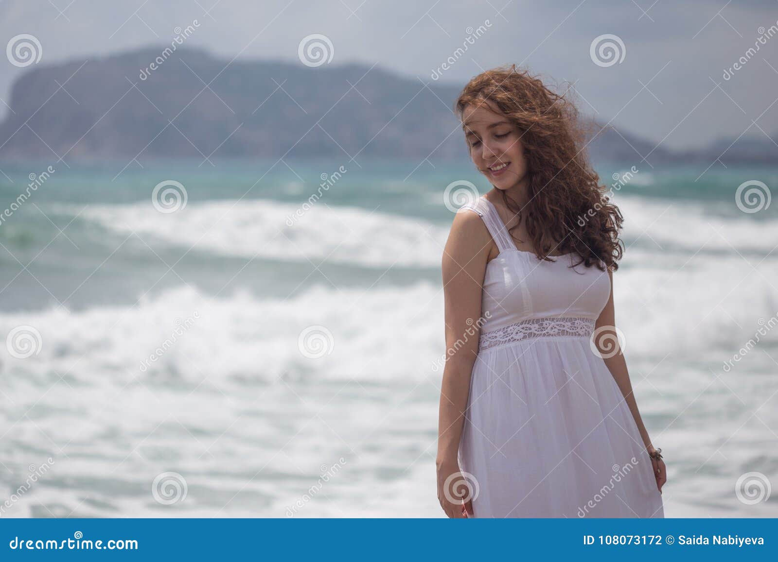 young brunette female with wavy hair wearing white dress