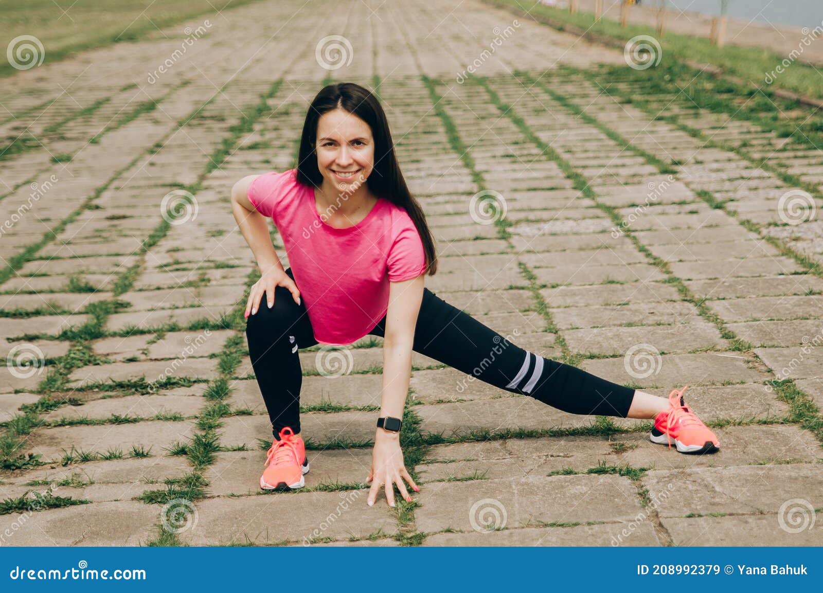 young brunette woman with bare feet  wearing black and purple fitness outfit  stretching on violet yoga mat outside on wooden pier