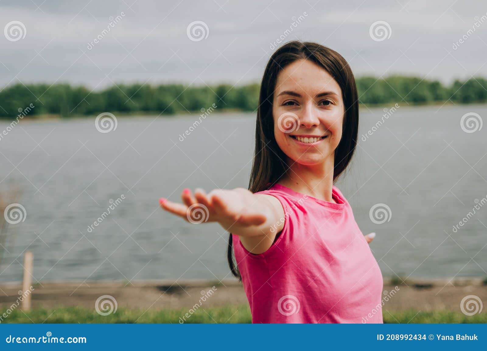 young brunette woman with bare feet  wearing black and purple fitness outfit  stretching on violet yoga mat outside on wooden pier